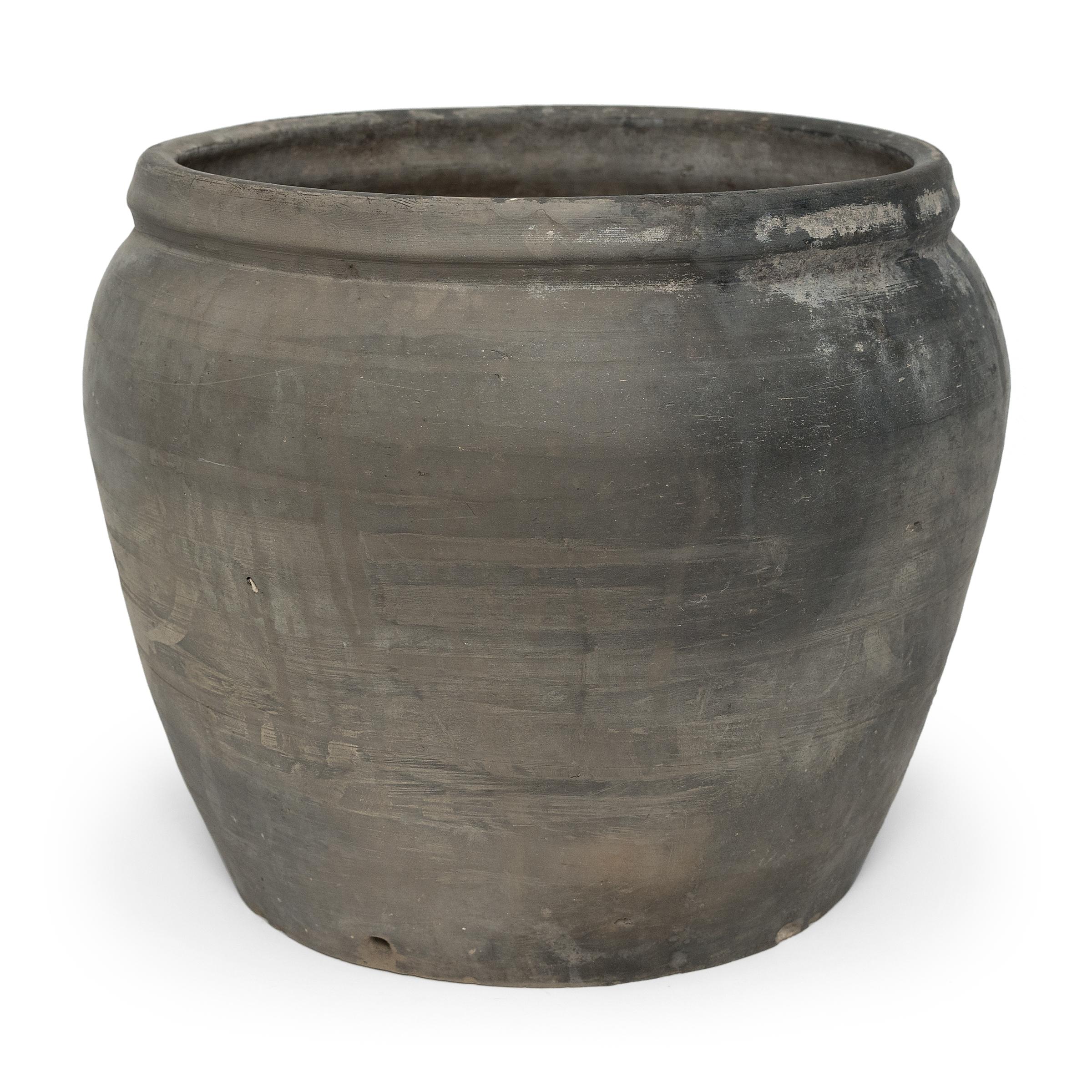 Sculpted during the early 20th century in China's Shanxi province, this vessel has a smoky grey-black exterior with balanced proportions and a beautifully irregular unglazed surface. Charged with the humble task of storing dry goods, this