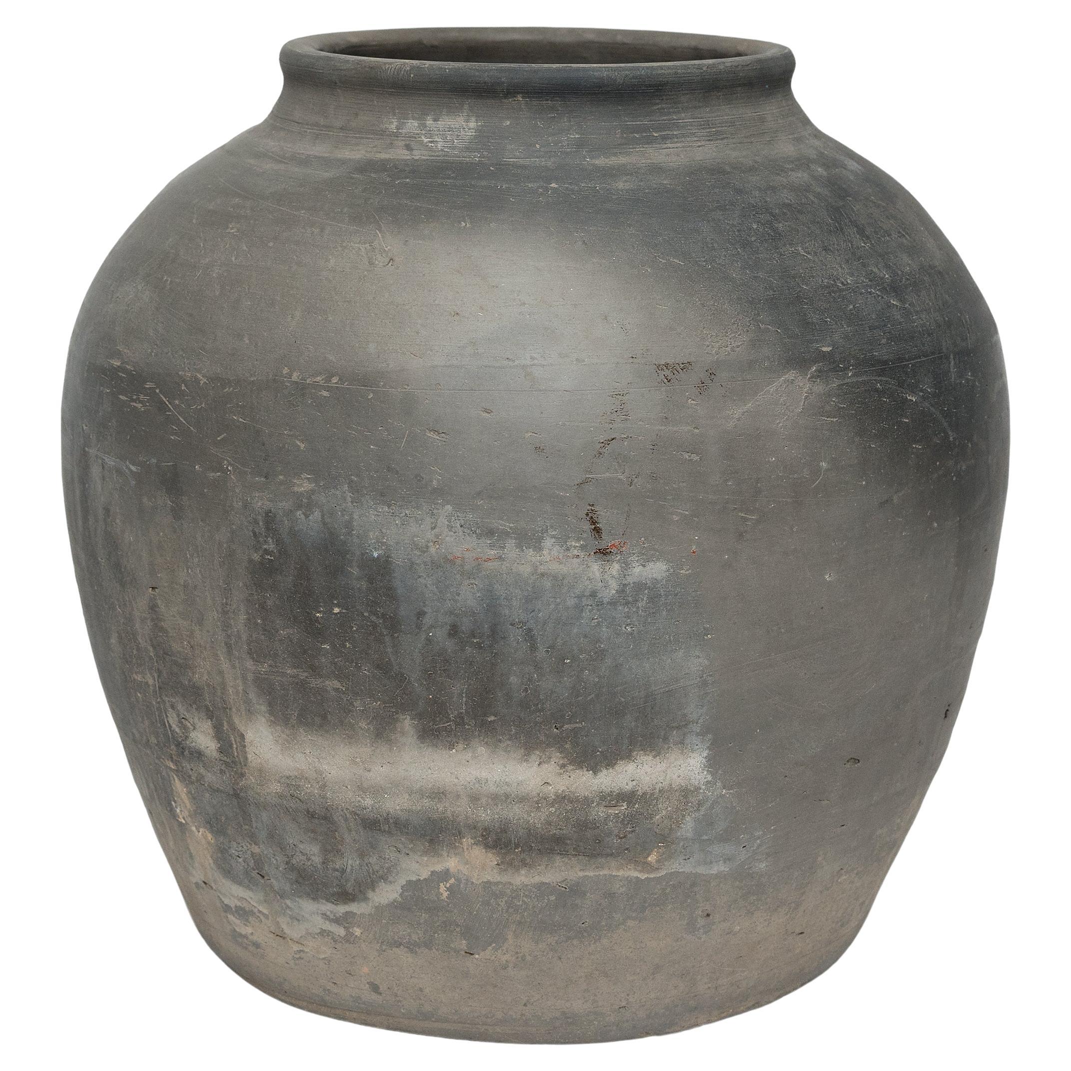 Sculpted during the early 20th century in China's Shanxi province, this vessel has a mottled grey exterior with balanced proportions and a beautifully irregular unglazed surface. Charged with the humble task of storing dry goods, this earthenware