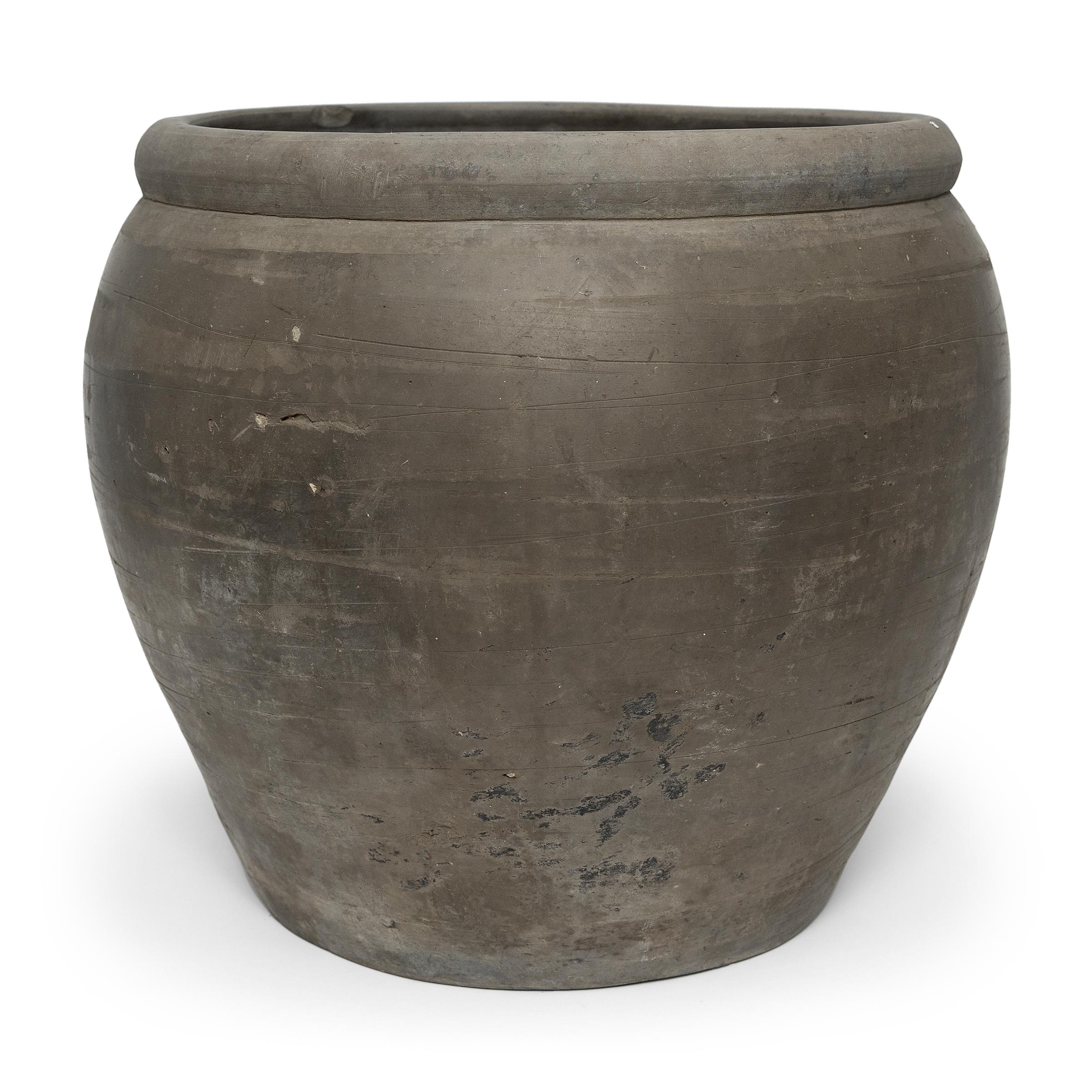 Sculpted during the early 20th century in China's Shanxi province, this vessel has a smoky black exterior with balanced proportions and a beautifully irregular unglazed surface. Charged with the humble task of storing dry goods, this earthenware jar