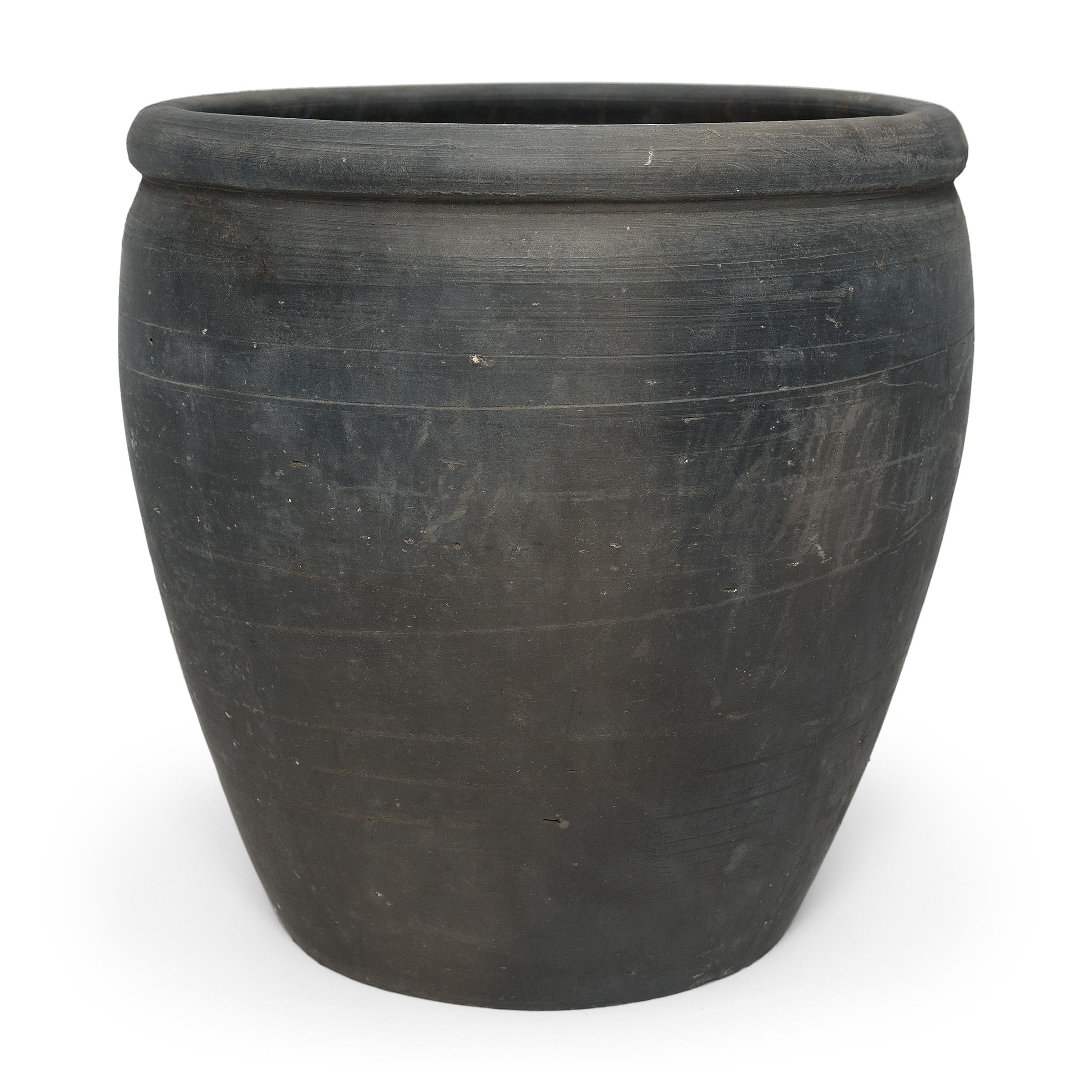 Sculpted during the early 20th century in China's Shanxi province, this vessel has a smoky black exterior with balanced proportions and a beautifully irregular unglazed surface. Charged with the humble task of storing dry goods, this earthenware jar