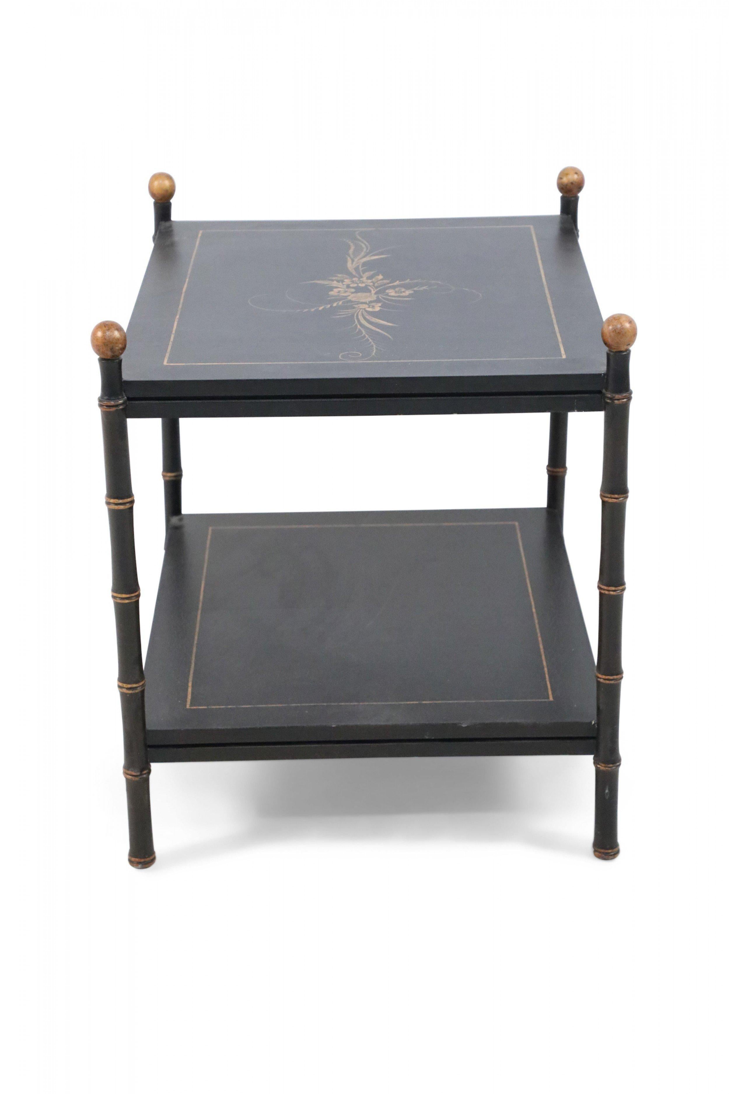 Chinese black end table with two tiers supported by gold-accented faux bamboo legs, and painted with gold borders and a floral motif decorating the top shelf.
 