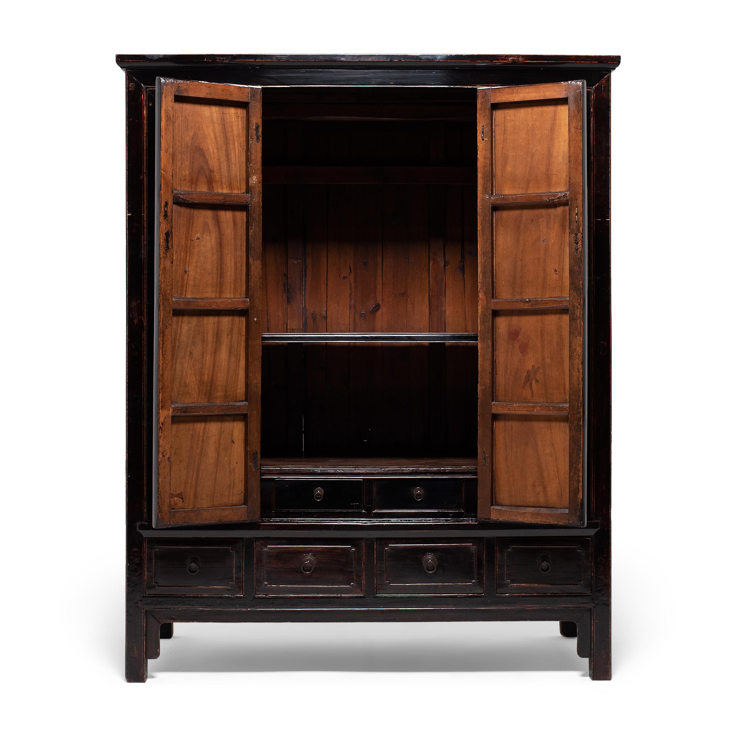 This grand black lacquer cabinet epitomizes the austere beauty of classical Chinese furniture design. Dated to the mid-19th century, the tall cabinet was crafted in Zhejiang province of camphor wood (changmu), a common material for storage chests
