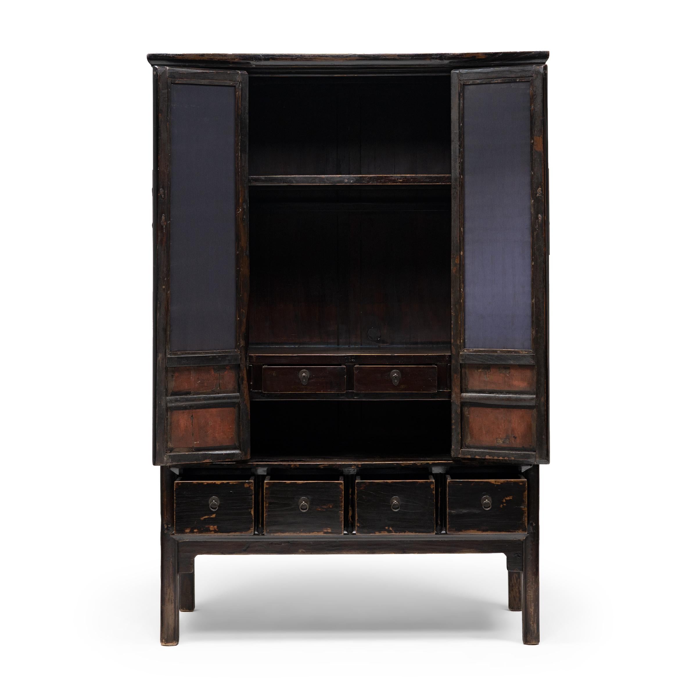 Avec ses lignes épurées et sa finition laquée sombre, ce meuble d'angle carré célèbre la sobriété des formes classiques du mobilier chinois. Datée du milieu du XIXe siècle, cette grande armoire est fabriquée en bois d'orme avec une menuiserie
