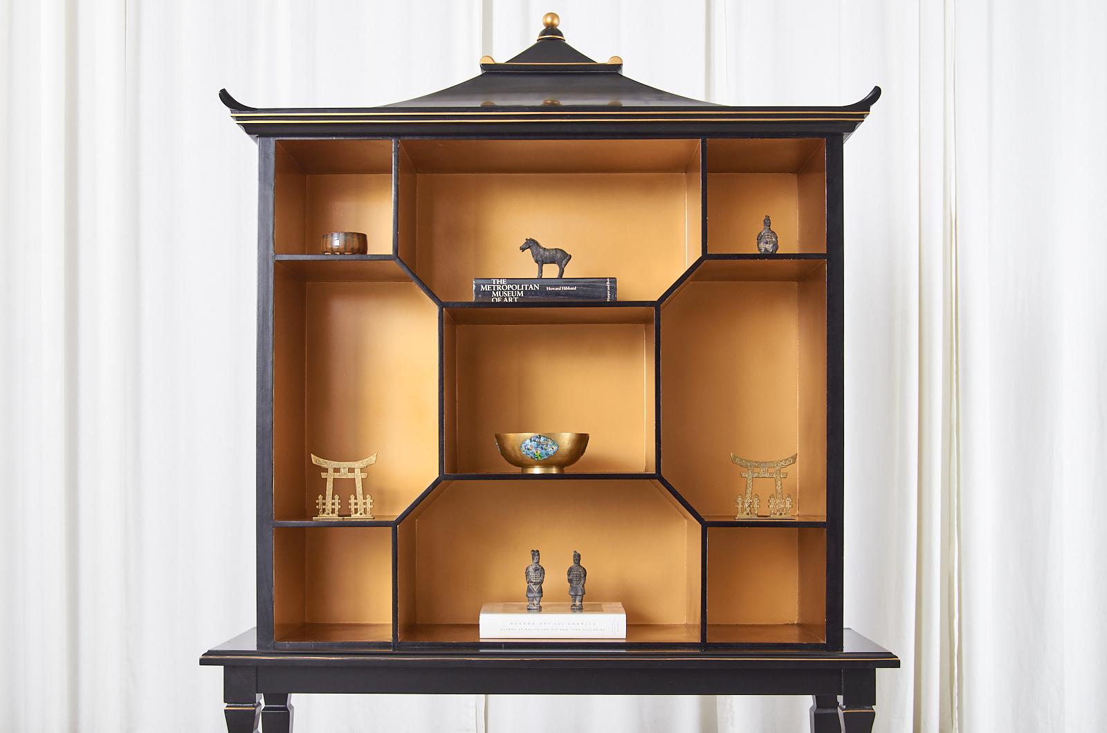 Contemporary Chinese two-part bookshelf, etagere, or store display shelves featuring an Asian pagoda top. Finished in a dramatic black lacquer ebony with parcel gilt accents and interior. The top is fitted with shelves or cubbies measuring 14.5
