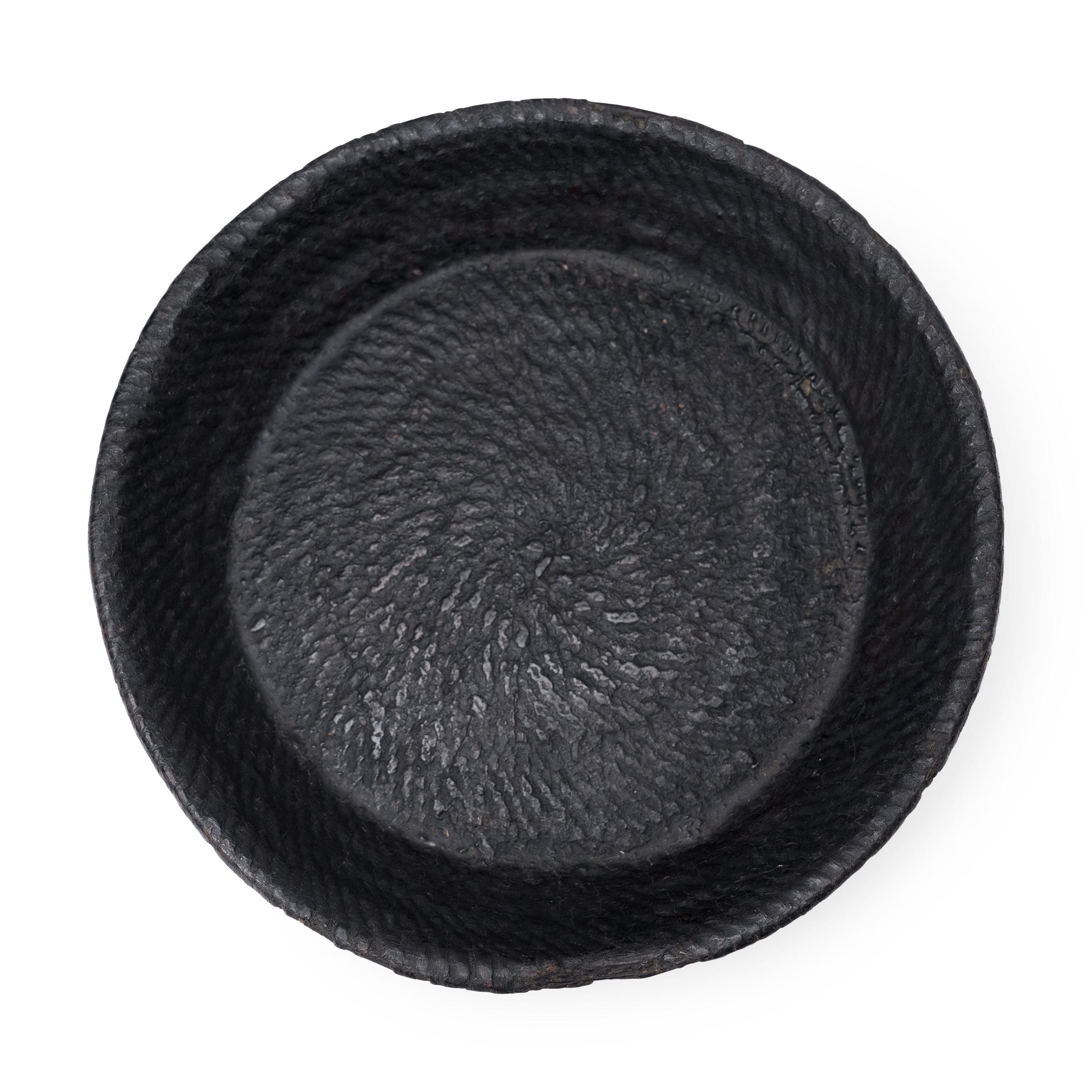 Questo piccolo vassoio intrecciato dell'inizio del XX secolo celebra la bella semplicità di un oggetto intrecciato a mano. Il piatto rotondo viene modellato con canne o bambù strettamente intrecciati e rifinito con uno spesso strato di thayo, una