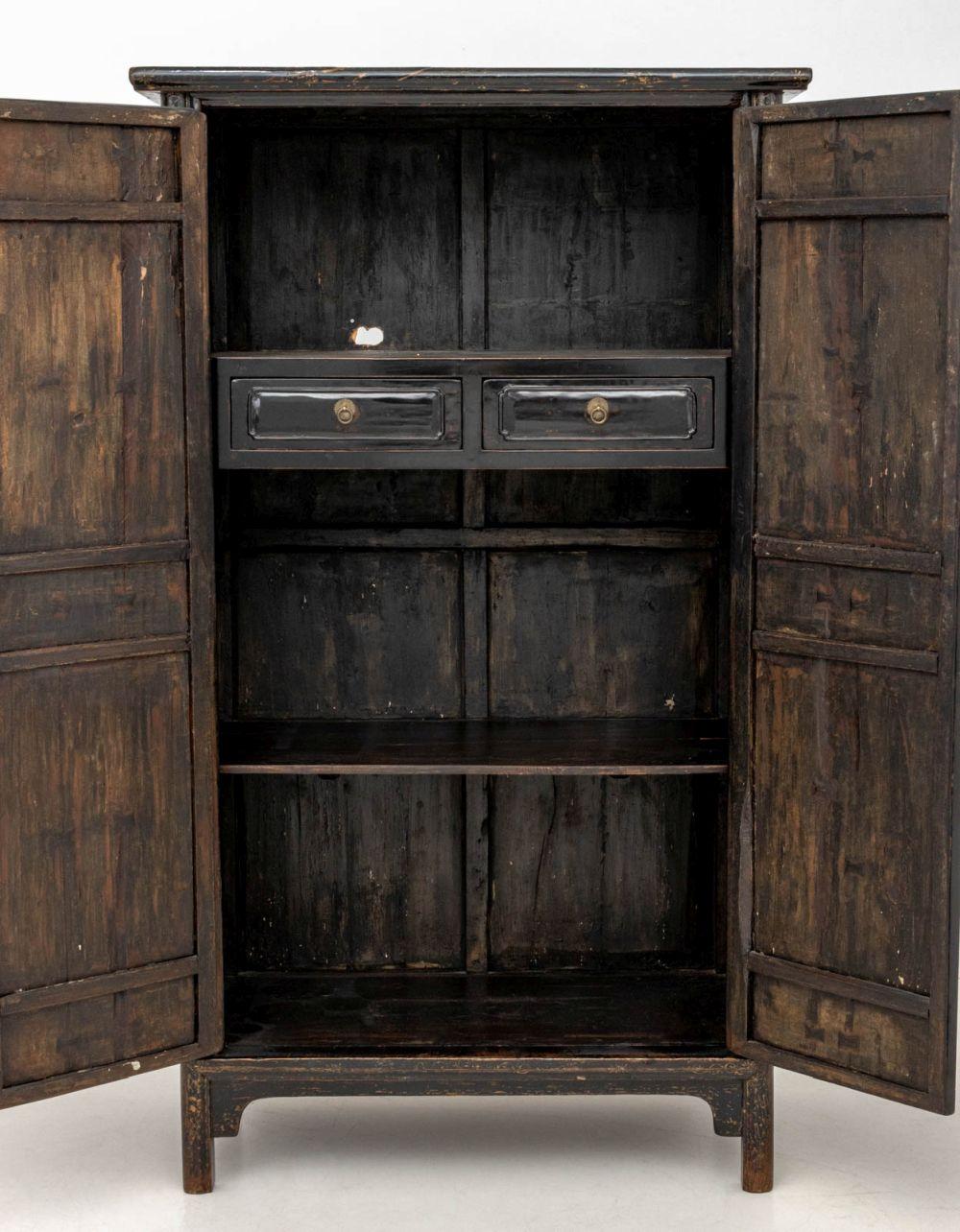 Armoire cinese a due ante laccato nero, XIX secolo, con motivo di cortile figurato dipinto e dorato, le due ante si aprono su tre ripiani e due cassetti corti su piedi a staffa. 
80