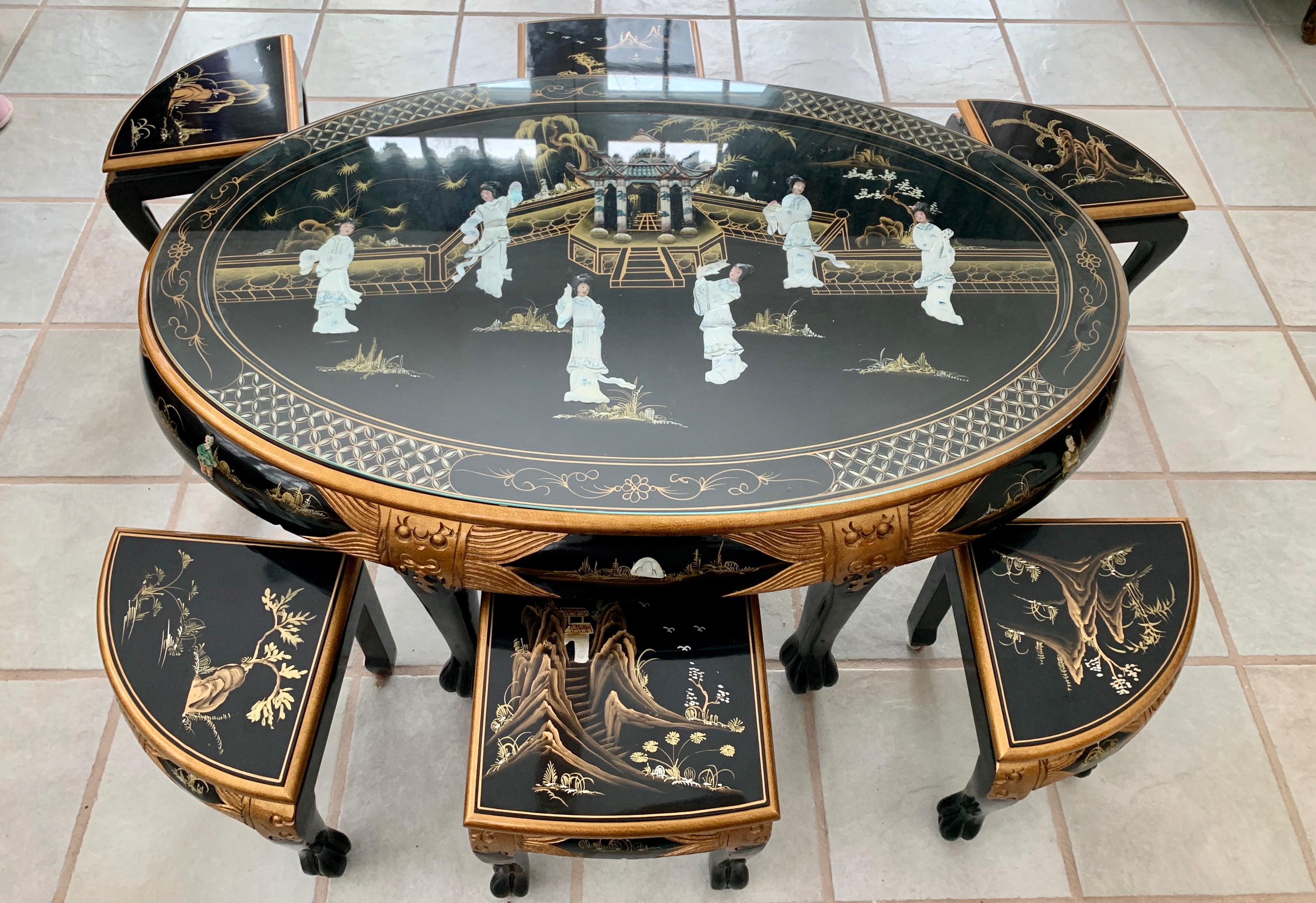 Chinese black lacquer and gold tea table set with 6 triangular stools. Each piece is hand-crafted from sturdy Elm wood and finished with a rich black lacquer. Top of table is a scenery of Chinese women around a temple and is Hand-carved from mother
