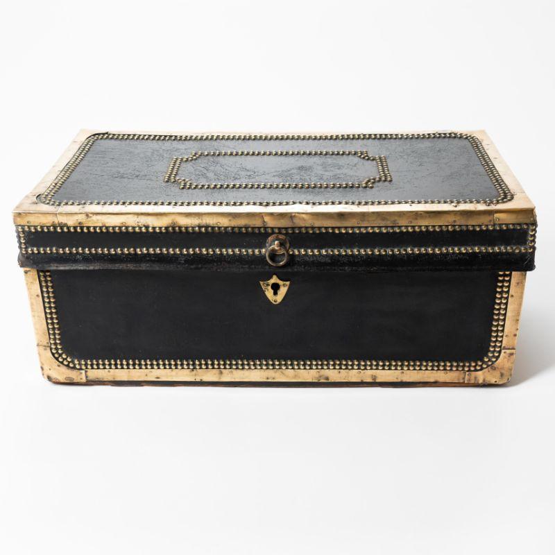 China trade brass bound black leather covered camphor wood trunk. The top and case are framed by brass corner mounts and brass tacking with a reserve of brass tacking on the center of the lid. The case is fitted with heavy cast brass bail handles