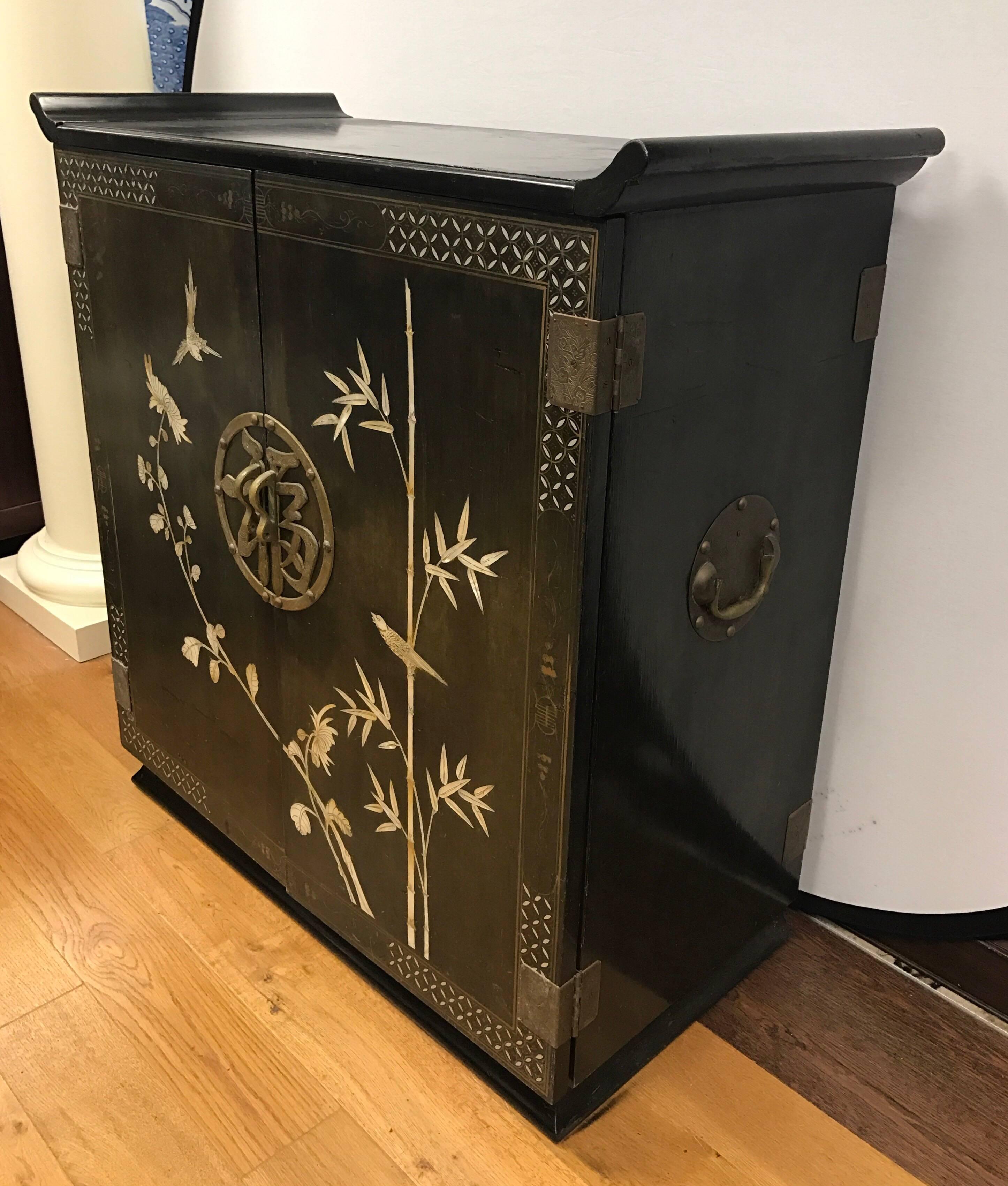 Unique Chinese black bar, liquor cabinet with beautiful detailed mother-of-pearl inlay of love birds and flowers on both the front and the hinged top that opens. Front doors open to shelves and storage. Top shelf pulls out and has wine glass