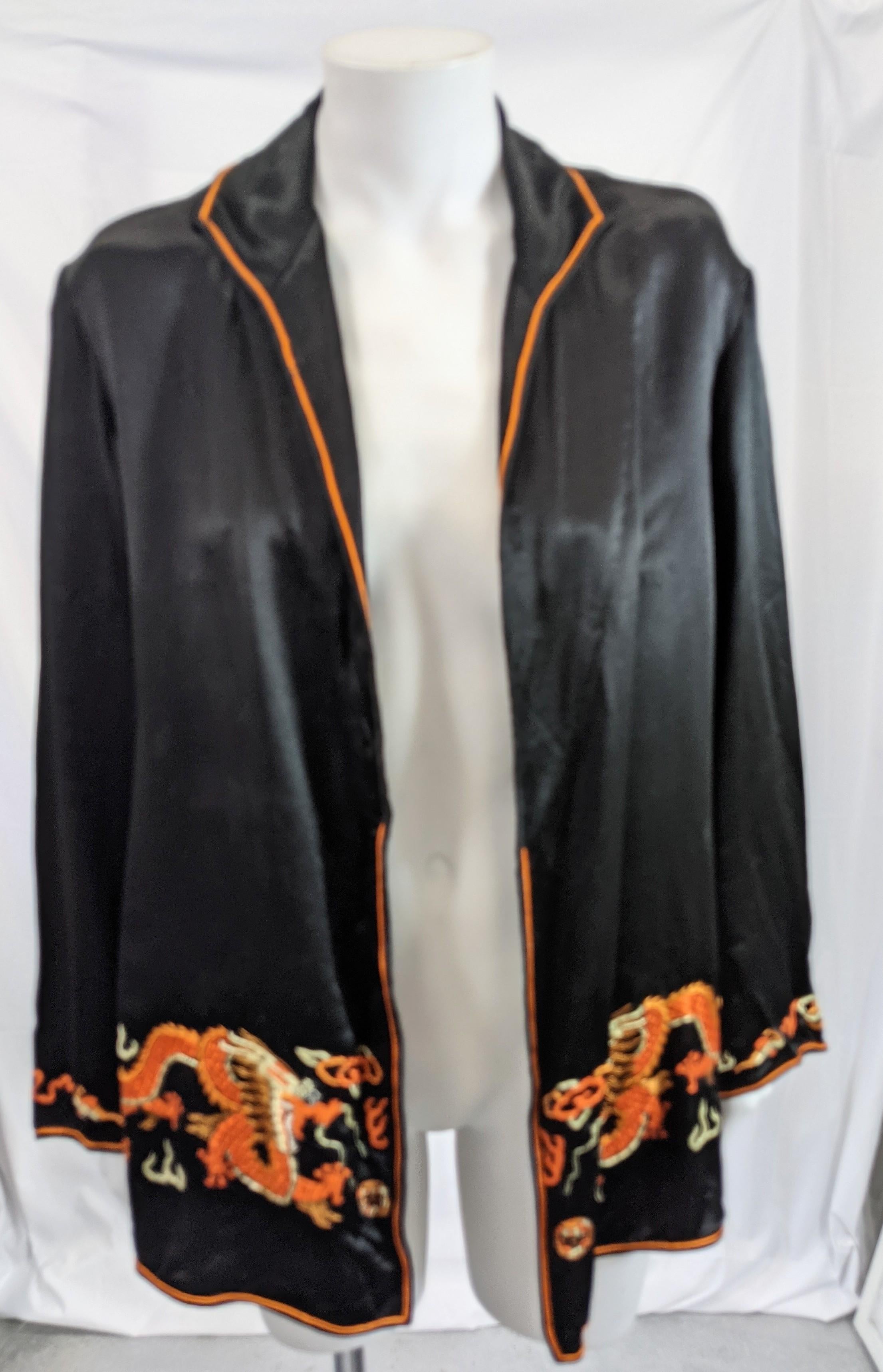 Chinese black silk satin unstructured jacket made for the Western market circa 1930. The jacket embroidered with orange and white dragons in blind stitch. Collar bias piped in orange silk satin. No closures on front but a hook or snap can easily be