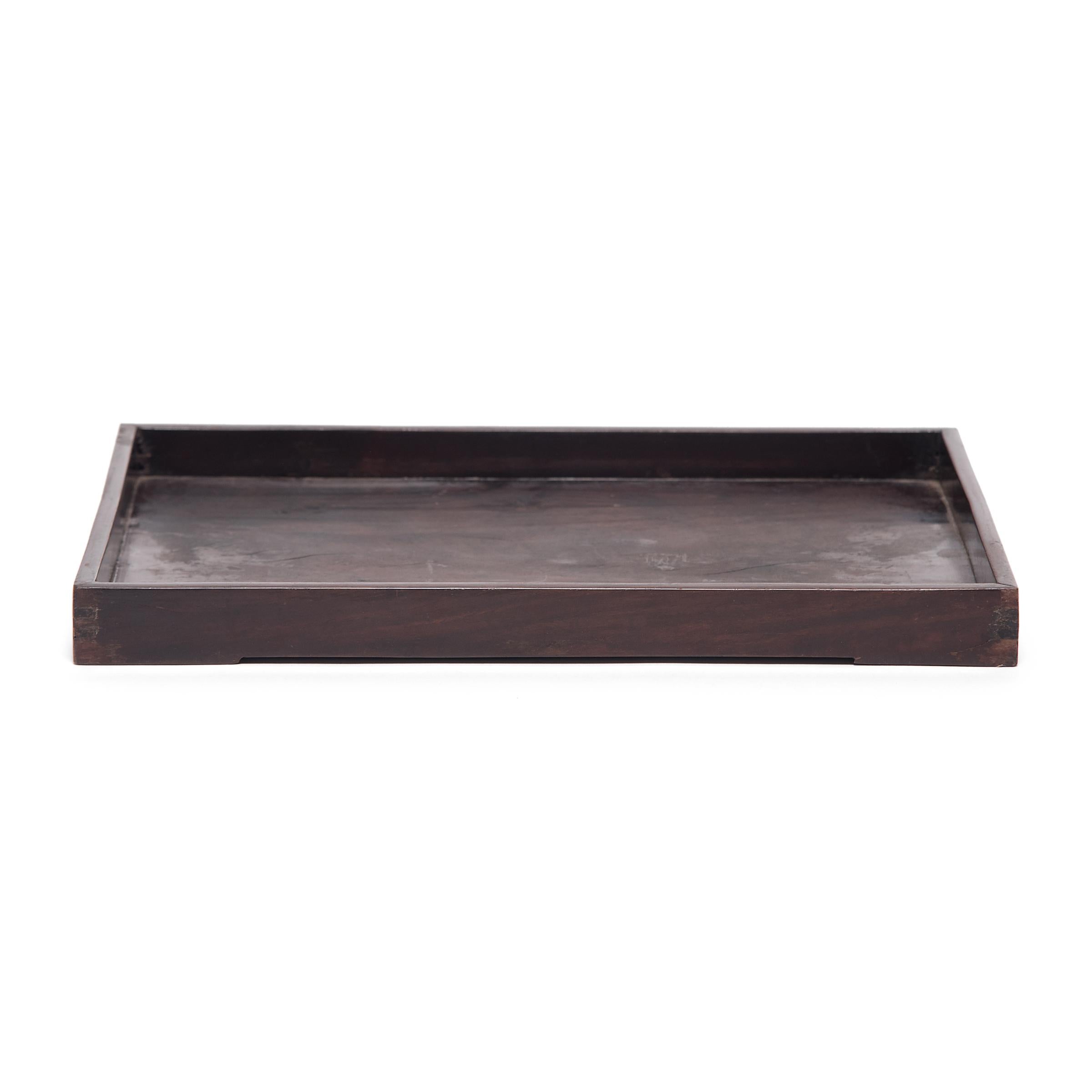 Crafted of fine blackwood, also known as hongmu, this 19th century tray once served tea or displayed calligraphy tools in a scholar's studio. Framed with low sides, the tray has a simple rectangular form to showcase the rich dark color and fine