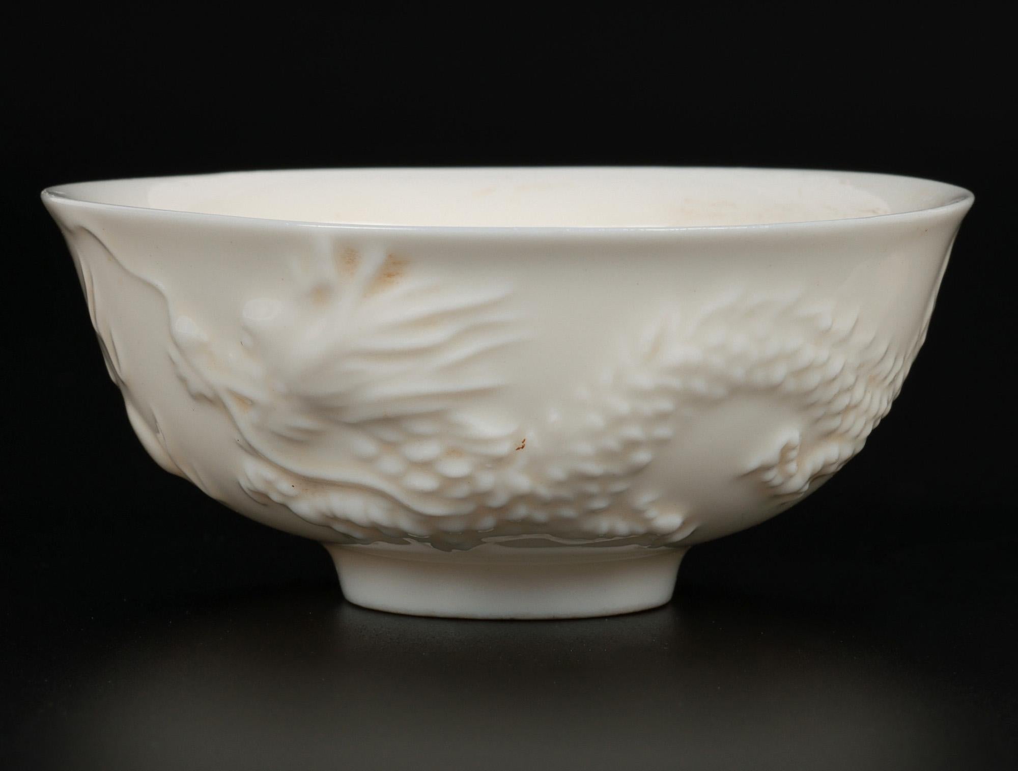 An antique set of three Chinese Blanc de Chine porcelain teabowls molded with dueling dragons chasing a flaming pearl and believed to date to the 18th century or possibly earlier. The bowls are very finely made in fine translucent white glazed