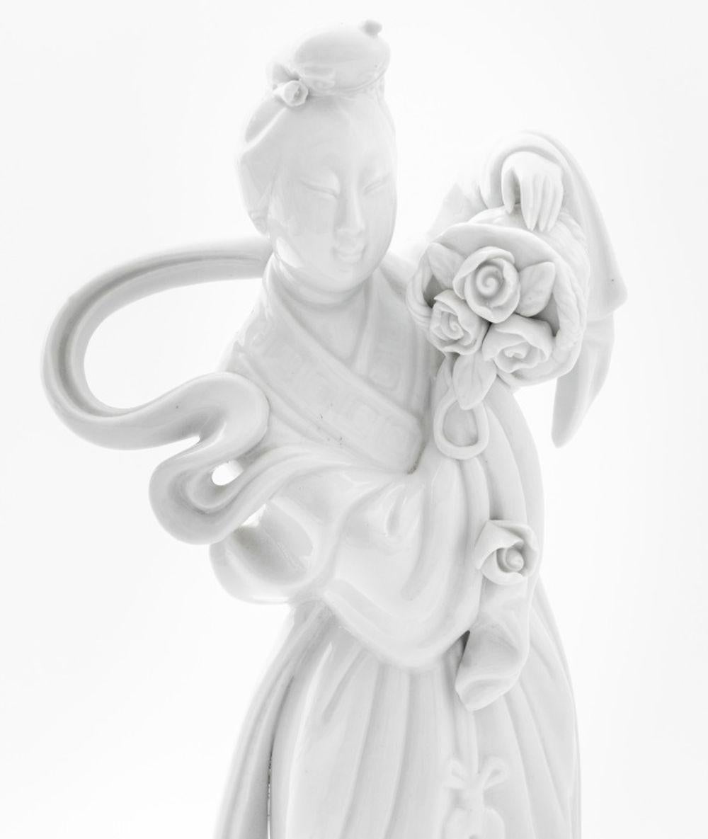 Paire de jeunes filles en porcelaine Blanc de Chine, chacune portant des paniers de fleurs. 12.25