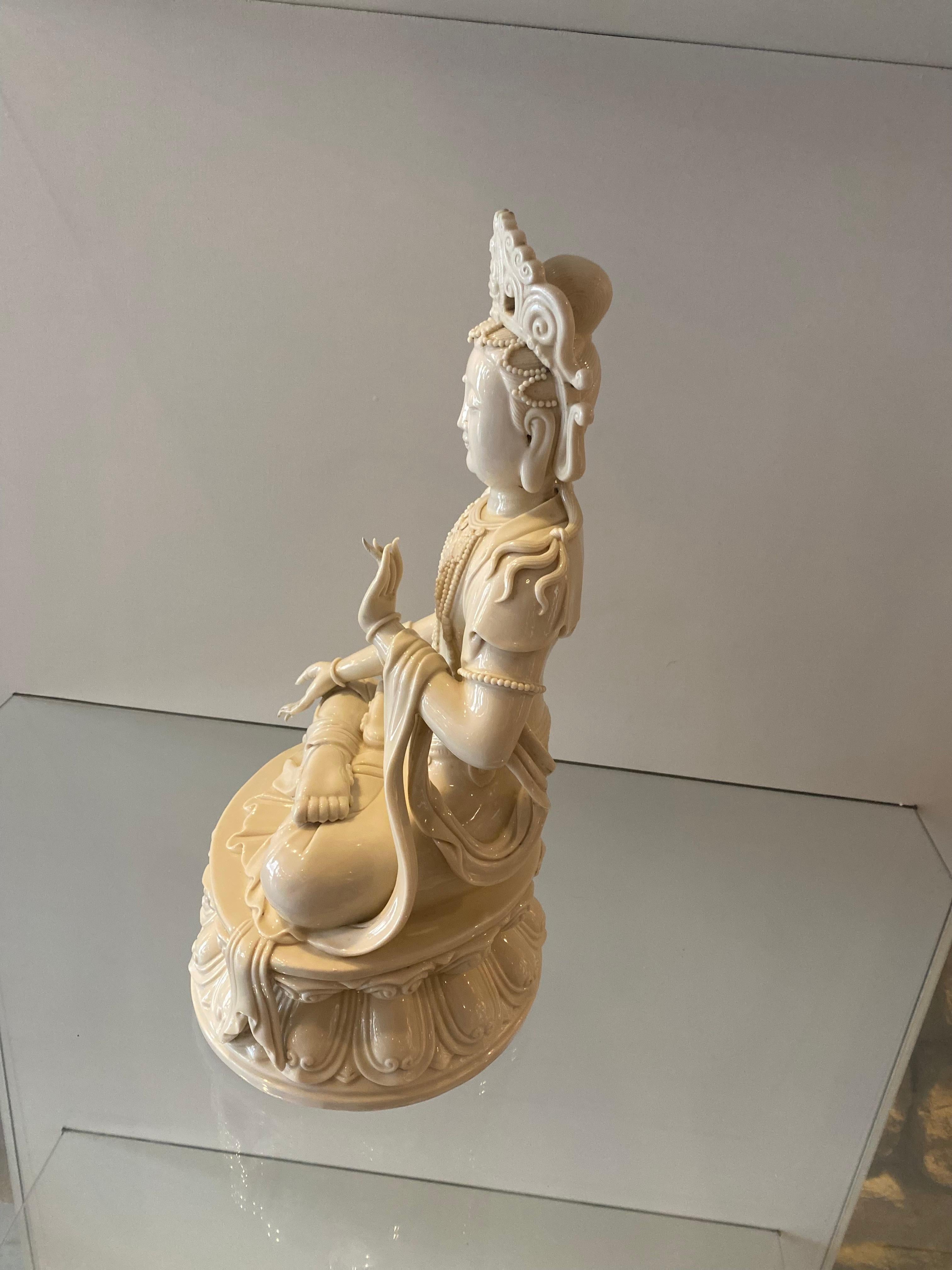This Porcelain Blanc de chine Statue of Gwen Yin sitting on a lotus blossom with her hands in the protection and overcoming fear. It has a chop mark on the back but can not be read.