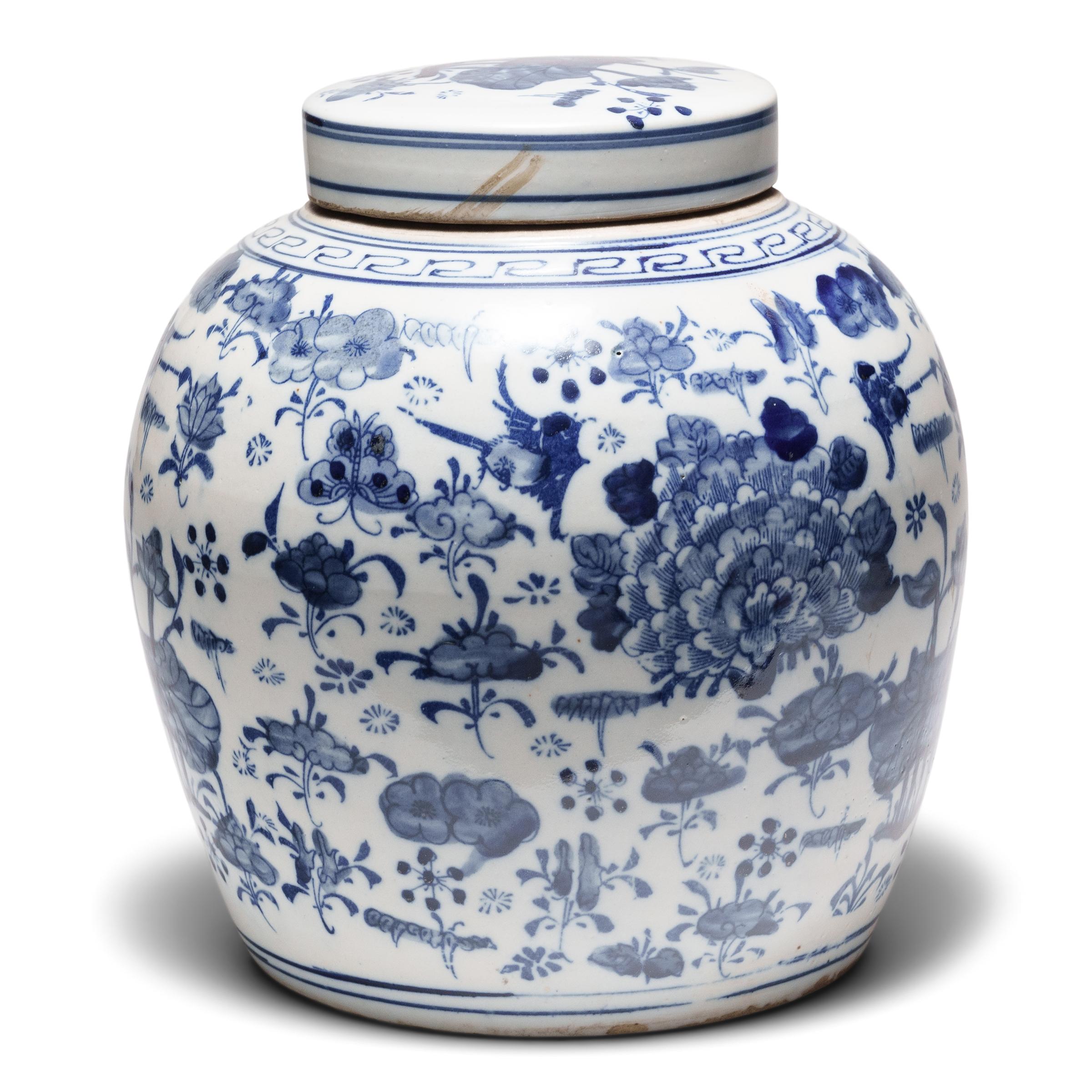 Questo vaso rotondo in porcellana è smaltato nel classico stile bianco e blu con un motivo botanico a tutto campo. Grazie alla combinazione di linee stencilate e ombreggiature spazzolate a mano, il vivace disegno è incentrato su peonie e fiori di