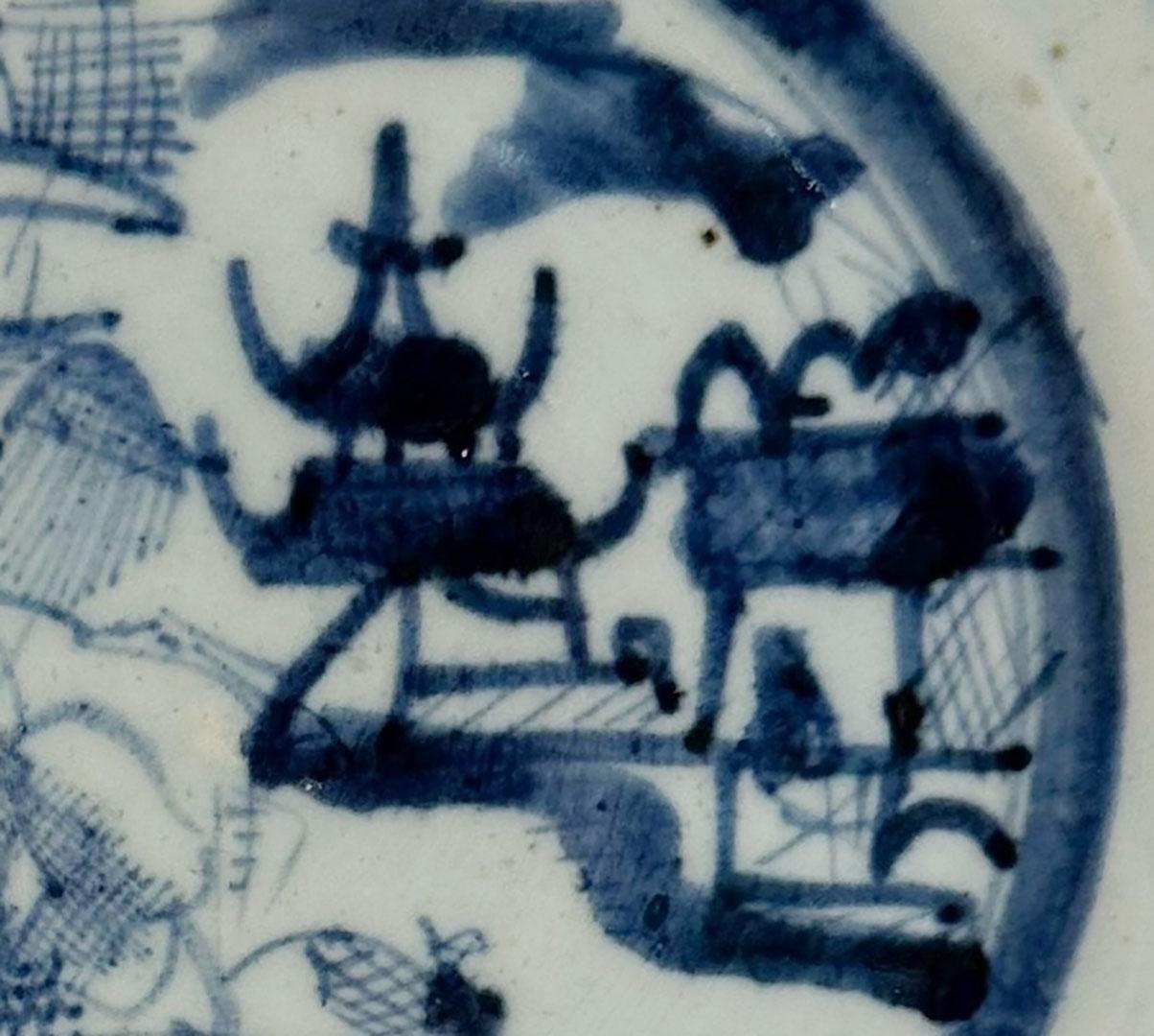 Ein feiner chinesischer Exportkantonteller aus dem frühen 19. Jahrhundert, handbemalt in tiefem Kobaltblau auf zartem weißen Grund. Dieses Werk zeigt die klassische kantonale Flusslandschaft mit Pavillons, Booten, Brücken und Bergen, Elemente, die