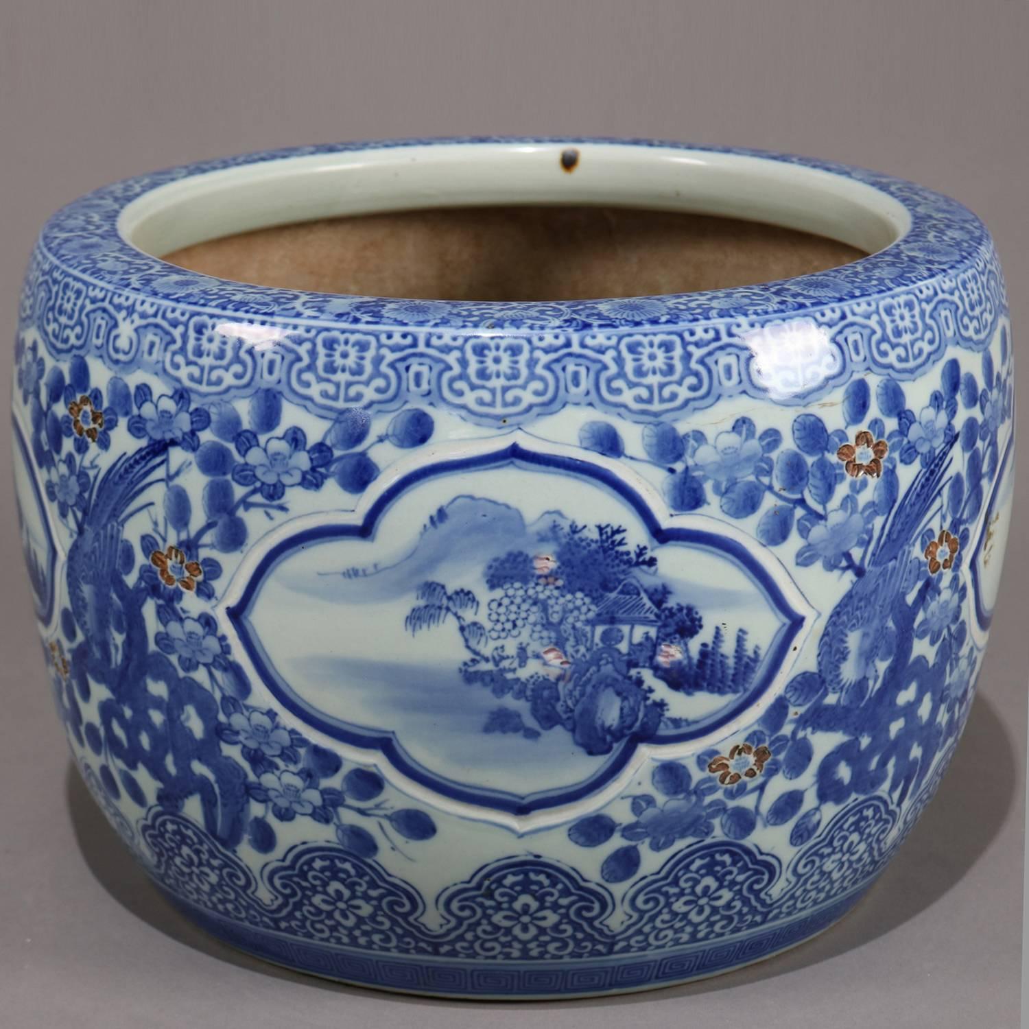 Chinese hand-painted blue and white fish bowl jardinière features reserves of landscape scenes among overall decoration foliate with Fenghuang phoenix, borders of repeating floral and scroll patterning, 20th century

Measures: 13.75