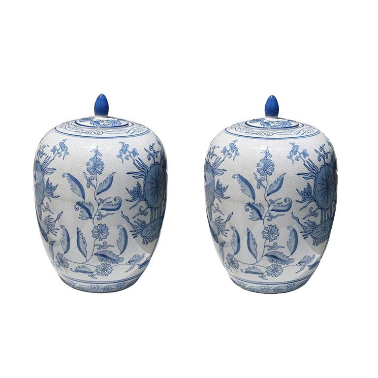 Two blue and white ceramic lidded faience ginger jars with covers. This pair of earthenware vessels feature a chinoiserie style Kangxi cobalt blue or Canton Blue and is hand-painted with a delf blue floral motif and underglaze on a creamy white