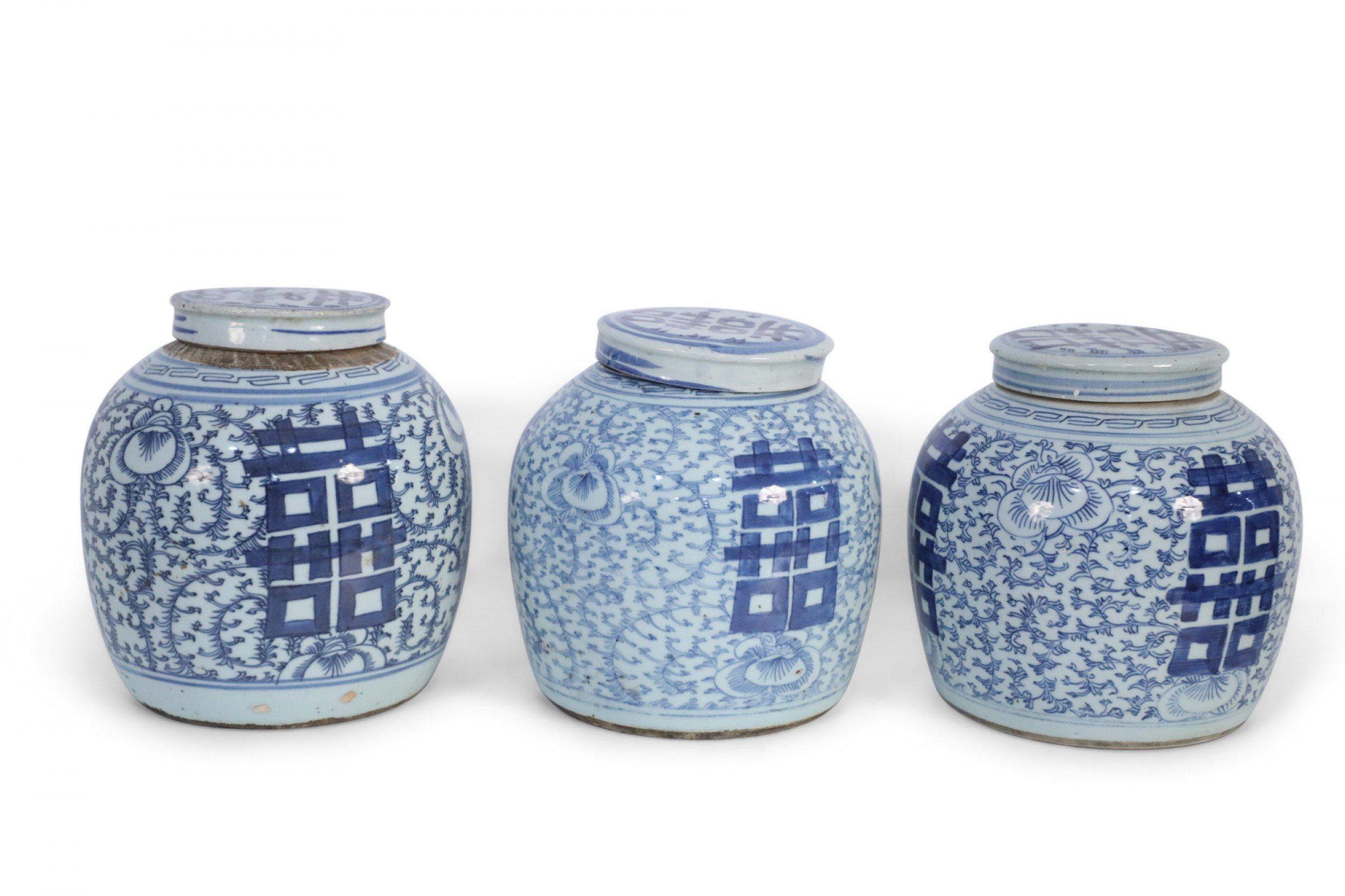 3 antique Chinese (Late 19th century) similar ceramic ginger jars with blue floral designs surrounding bold, centered characters and geometric patterned bands leading to brown rustic stripes at the mouth openings. Each is topped with a lid depicting