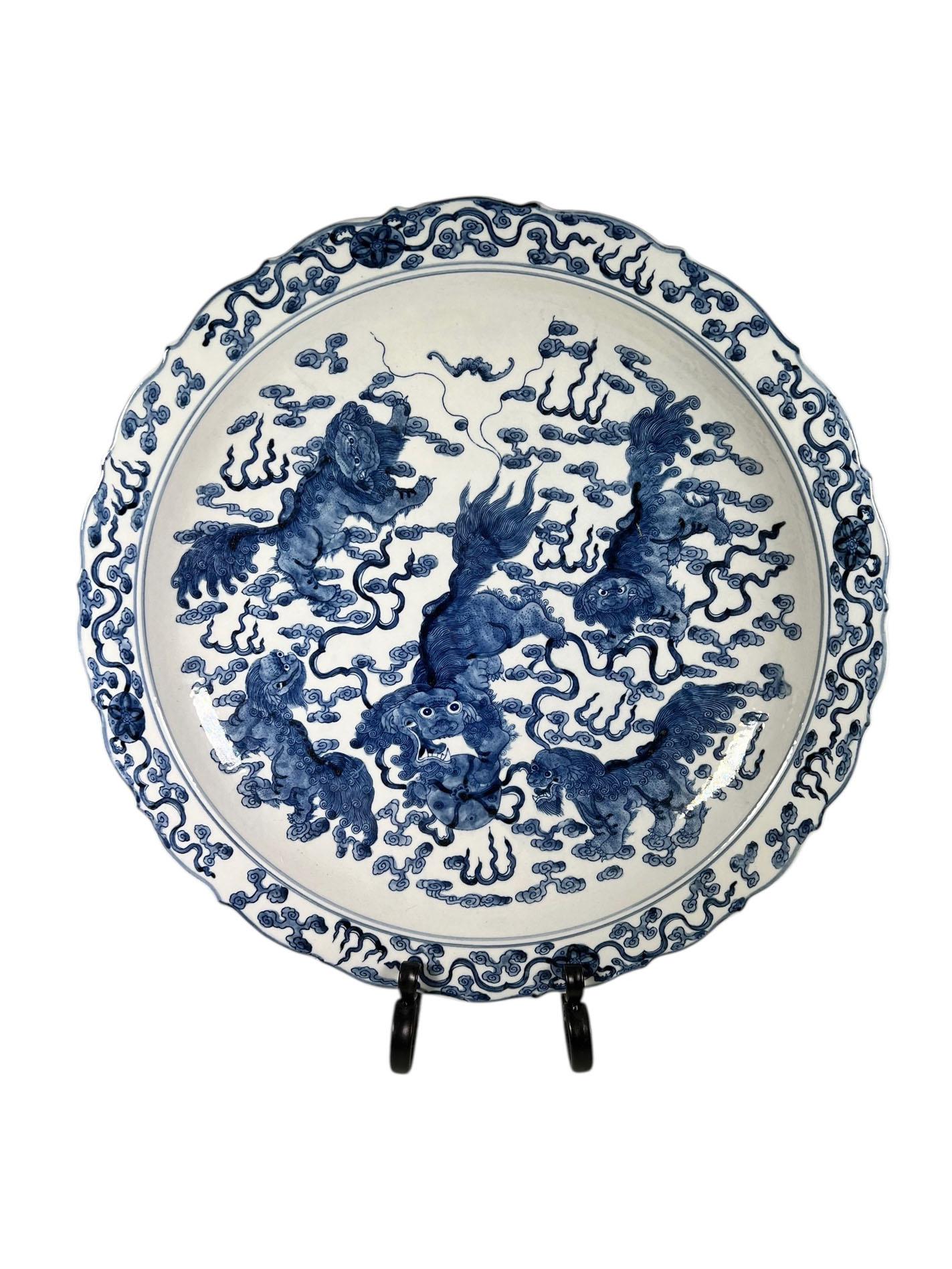 Une paire frappante de chandelles chinoises peintes en bleu et blanc, chacune présentant de magnifiques chiens de foo stylisés et de délicats rebords festonnés. La décoration peinte à la main est audacieuse et expressive, ce qui confère à la paire