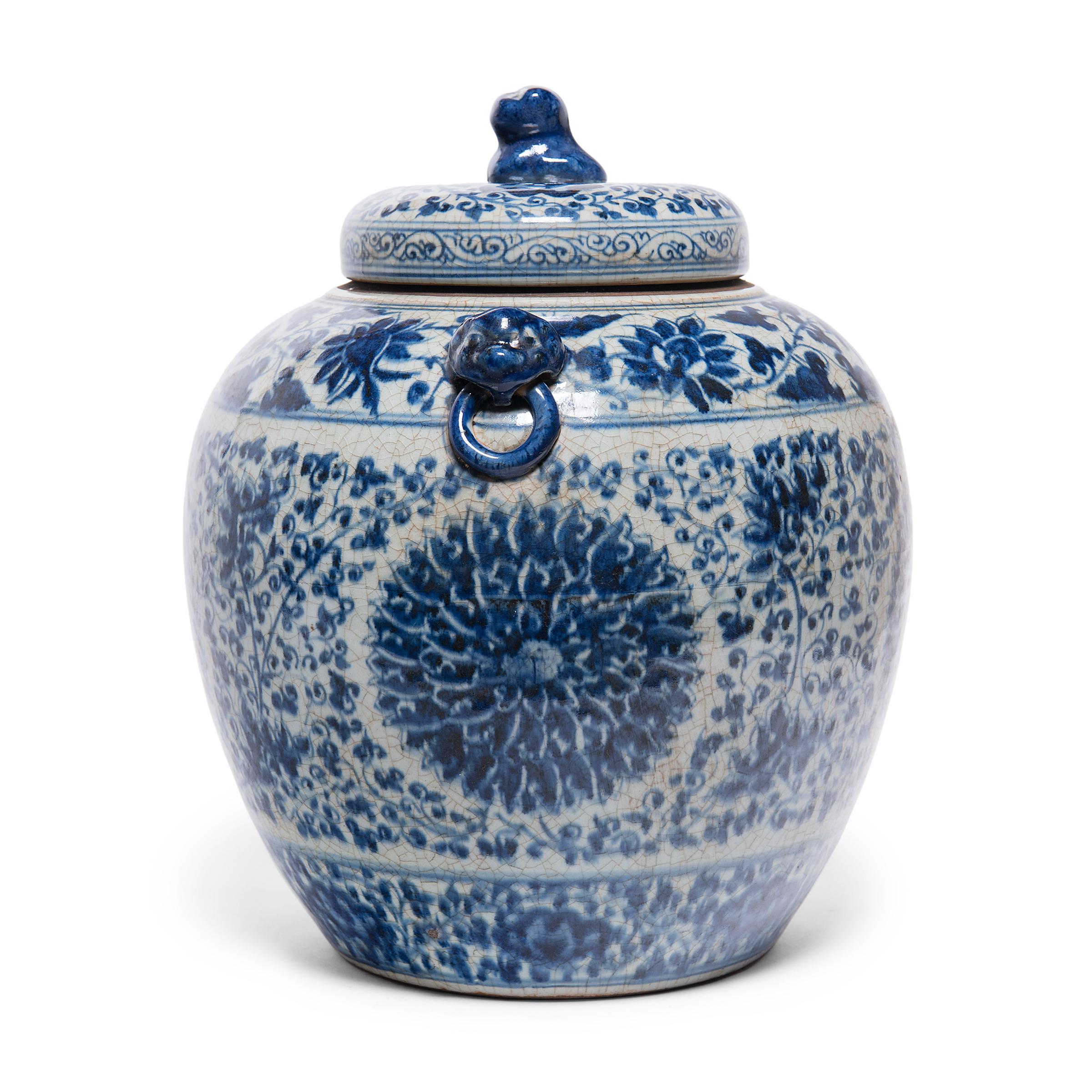 This gorgeous ginger jar continues a centuries-old tradition of Chinese blue-and-white porcelain ware. Painted with expressive brushwork, the jar is festooned with trailing vines and flower blossoms, densely patterned around large chrysanthemum