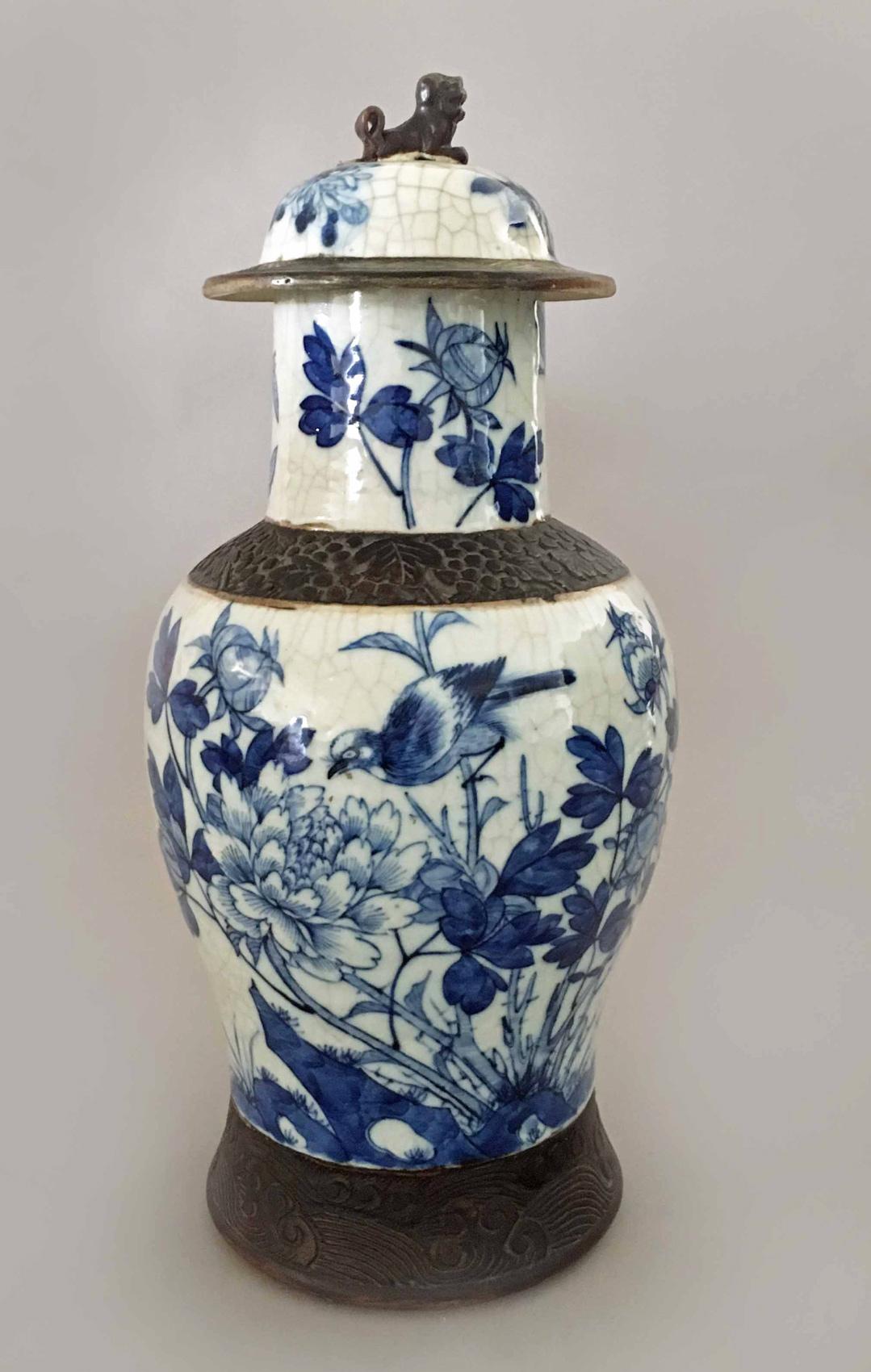 Chinese Export porcelain blue and white crackleware vase and cover decorated with birds, butterflies, peonies, chrysanthemums and foliage, the body having mat brown embossed collar and base, the cover with a foo dog finial. A brown date mark to the