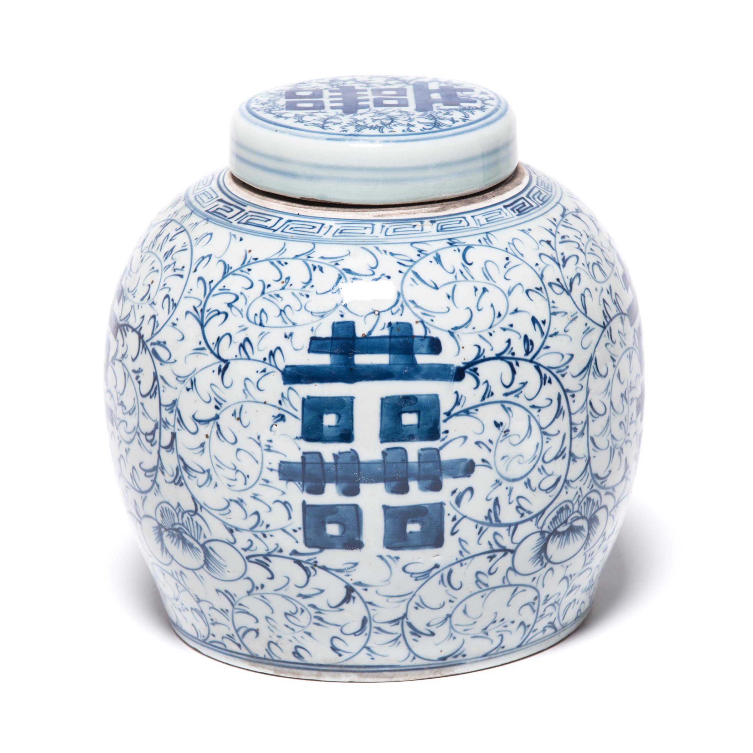 This early 20th century blue-and-white ginger jar was originally used for storing spices. Bordered by a simple meander, the jar is densely patterned with trailing vines and orchid blossoms, symbols of love and beauty. On either side of the round jar
