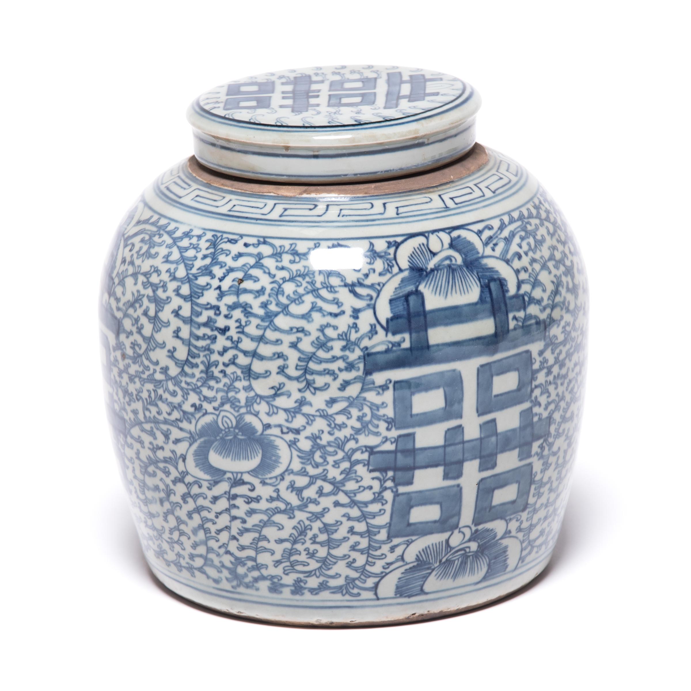 This early 20th century blue-and-white ginger jar was originally used for storing spices. Bordered by a simple meander, the jar is densely patterned with trailing vines and orchid blossoms, symbols of love and beauty. On either side of the round jar