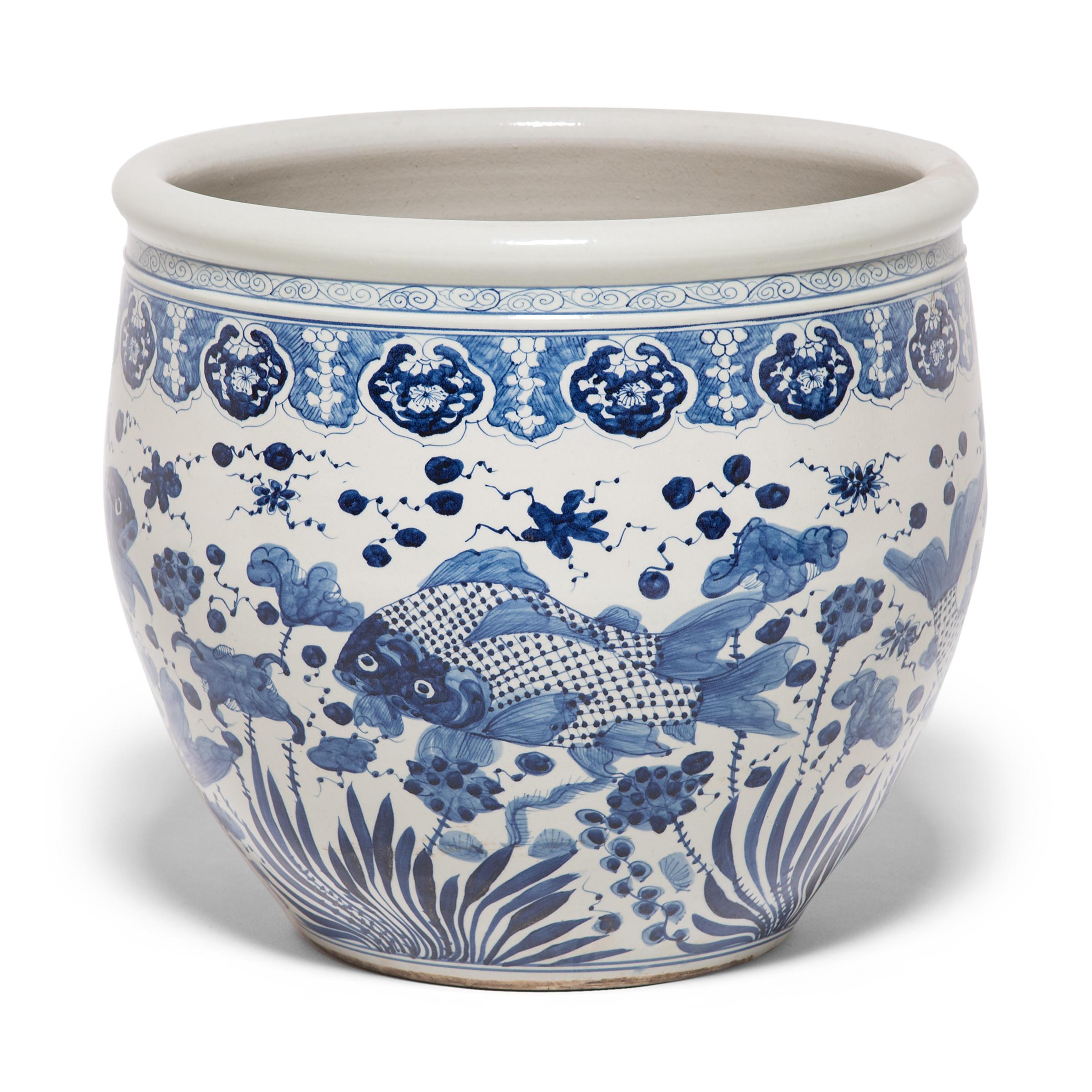 This grand, blue-and-white porcelain bowl is hand-painted with flora and fauna of the sea, offering blessings of wealth, abundance, and the contented harmony of a fish in water. Chinese blue-and-white ceramics have inspired ceramists worldwide since