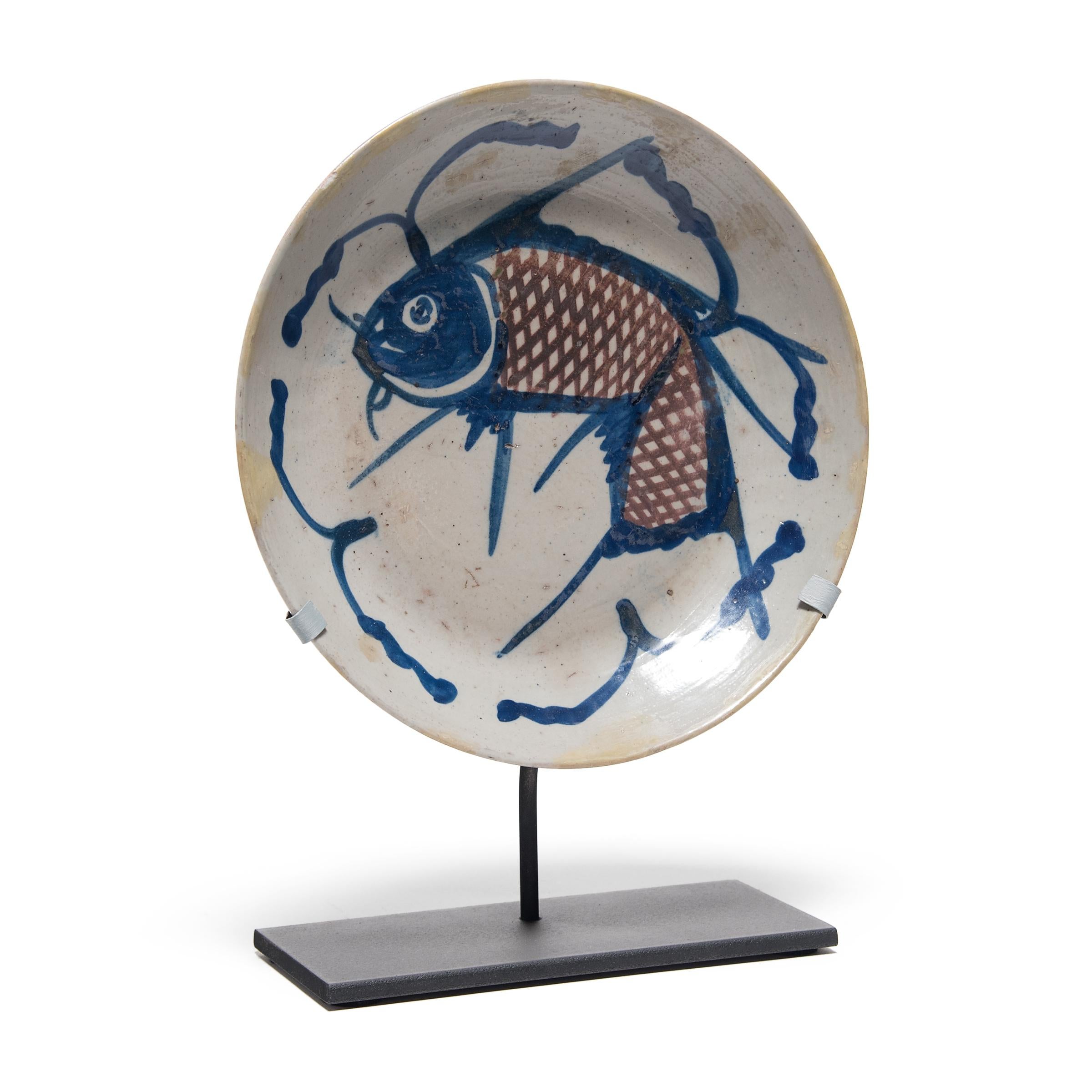 A traditional motif in Chinese art, the fish on this hand painted 19th century provincial plate represents a blessing for wealth. Chinese symbols take on added meaning and nuance when seen in combination. In this plate, the decorative blue lines