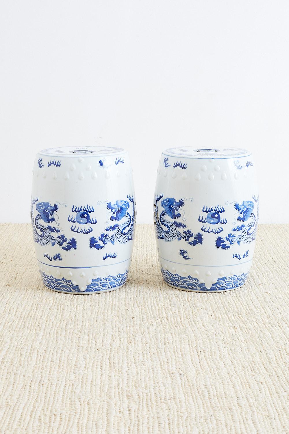 Pair of hand-painted Chinese blue and white ceramic garden stools or drink tables featuring flying dragons. Large cylindrical drum form stools with waves painted on bottom and a cloud design around the dragons chasing a flaming pearl of wisdom.