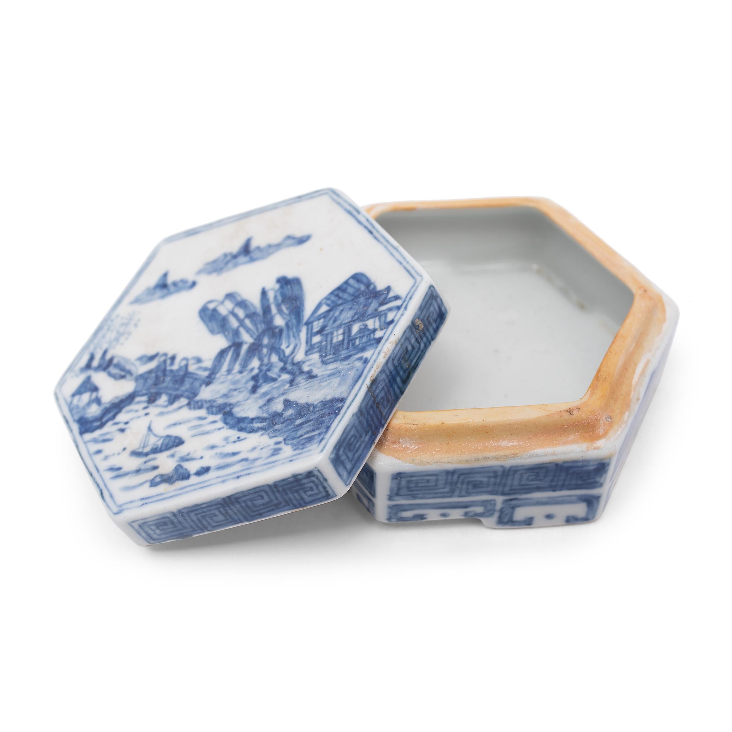 This petite porcelain box has a shallow, hexagonal form, similar to those traditionally used for seal ink or cosmetics. The six-sided box is glazed in the blue-and-white style, hand-painted with a serene, waterside landscape and simple spiral