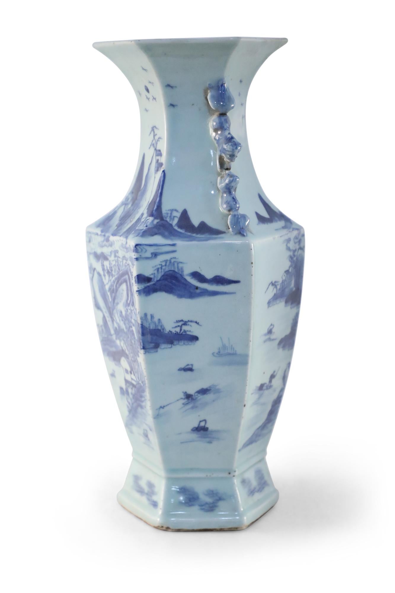 Antique Chinese (Early 20th Century) blue and white hexagonal-shaped porcelain vase depicting a village scene and surrounding nature and accented with blue scroll handles at the neck.
 