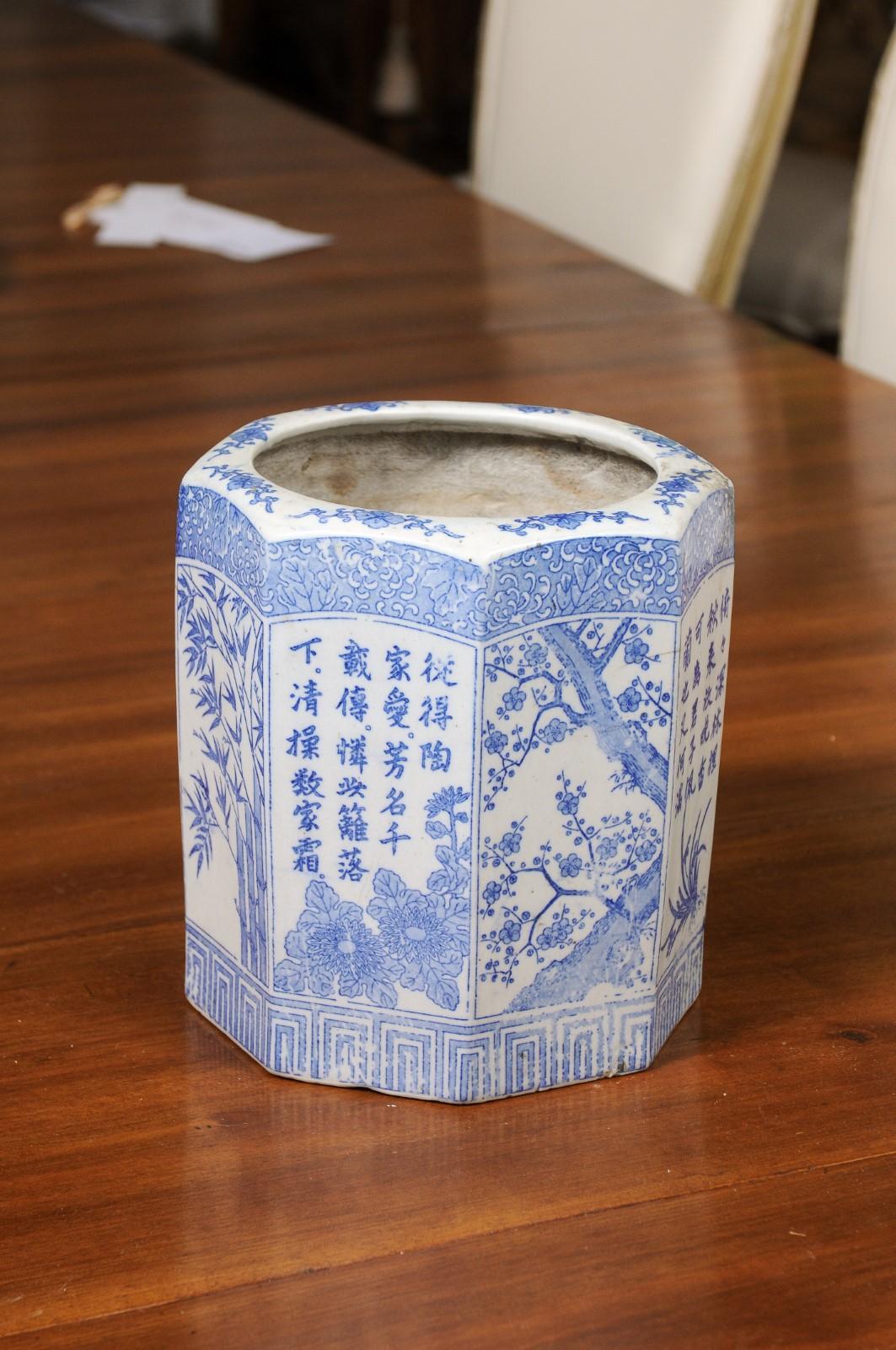 A Chinese blue and white hexagonal porcelain vase from the 20th century with hand-painted bamboo, flowers and calligraphy. Created in China during the 20th century, this porcelain vase features an hexagonal body adorned with a hand-painted blue