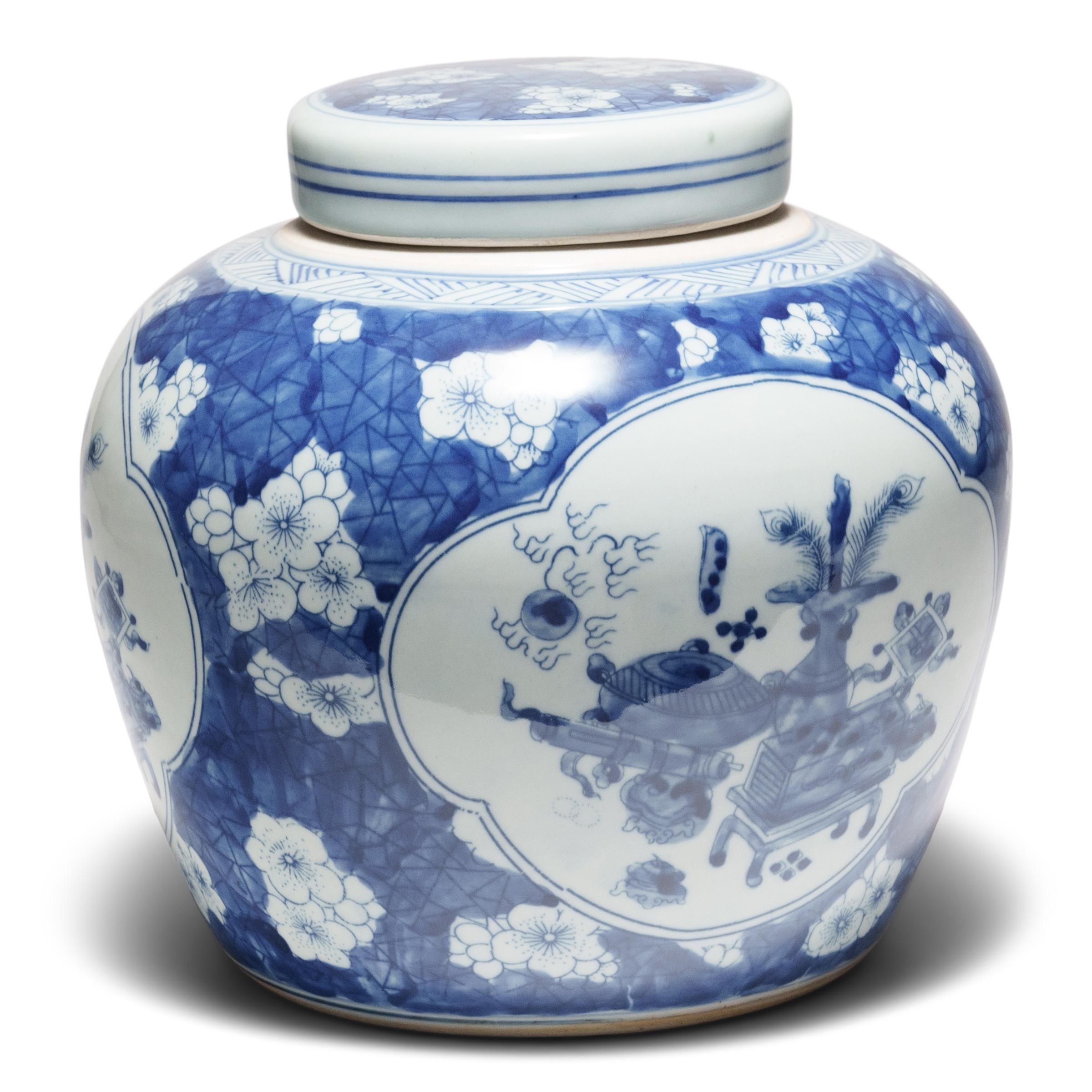 This porcelain storage jar has a rounded, tapered form and is brightly glazed in the classic blue-and-white manner. The jar is decorated on three sides with cartouches enclosing still life vignettes of scholars' objects. Among the precious objects