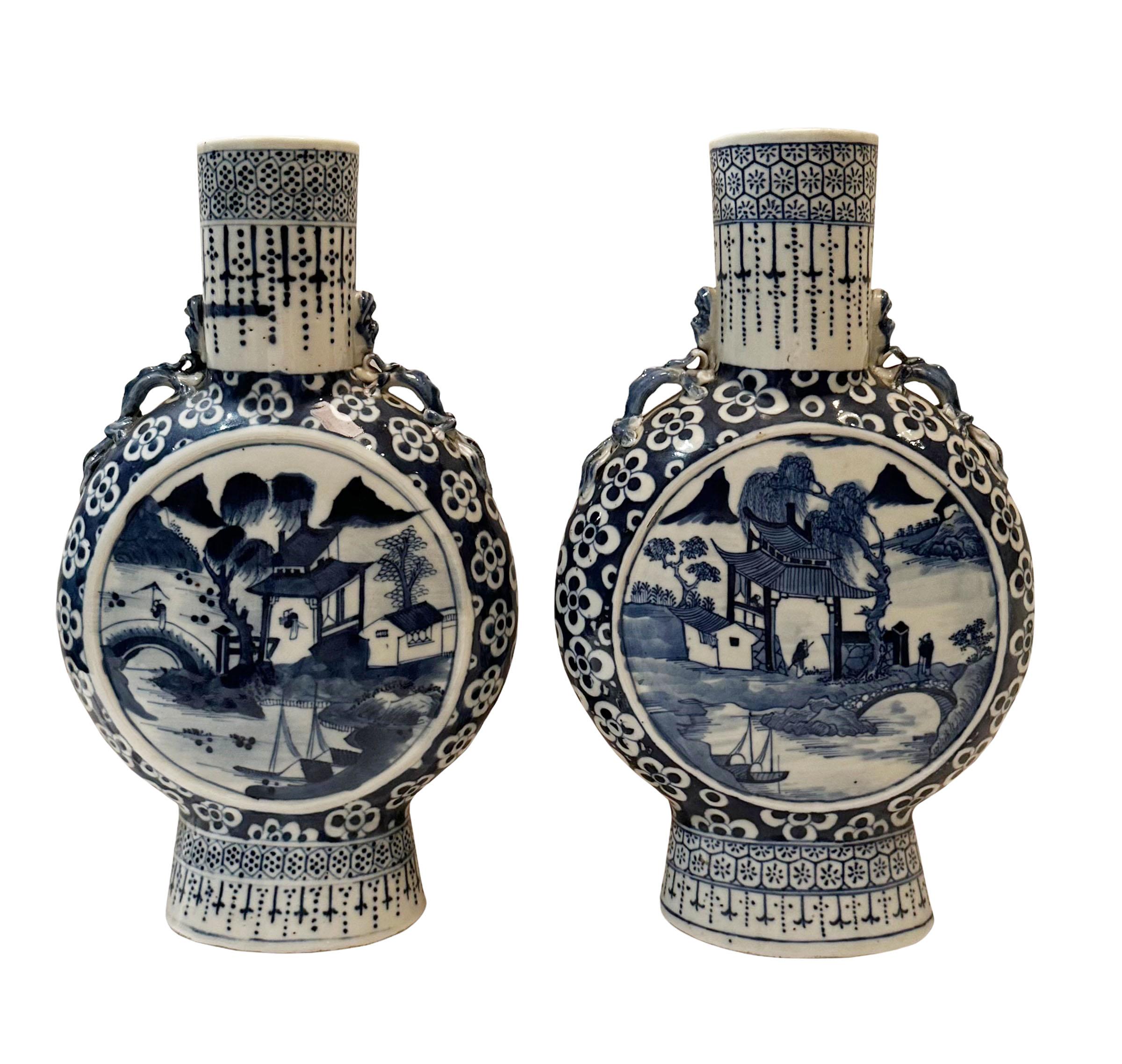 A pair of 19th century Chinese moon flask in blue and white. Depicting a pagoda with fishermen, a bridge and flowers and a pair of dragons on each vase. 