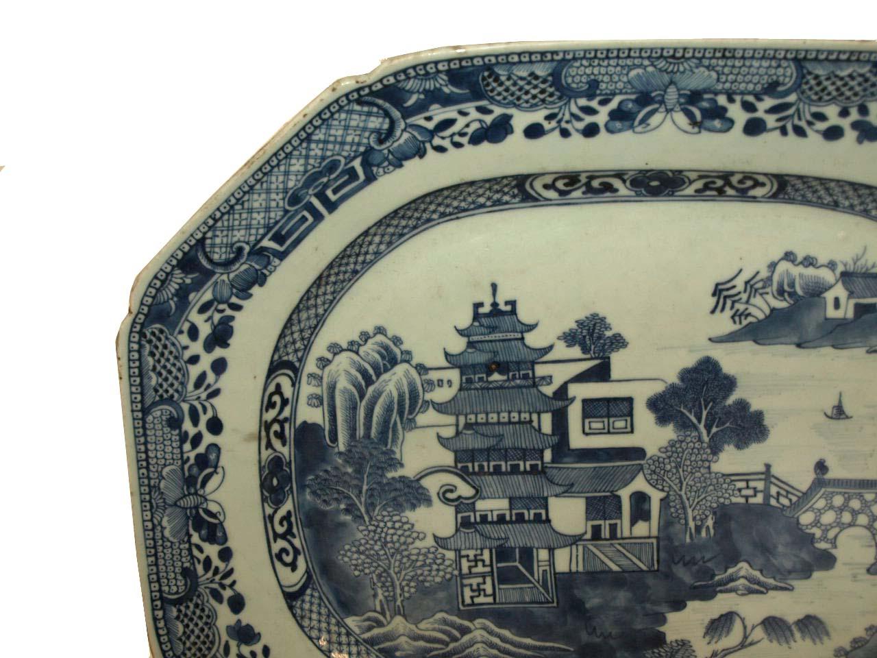 Chinese blue and white platter from the early 19th century, the border with various foliate work, the interior of the platter featuring the classic landscape of pagotas, river and bridge. This platter is in very good condition.