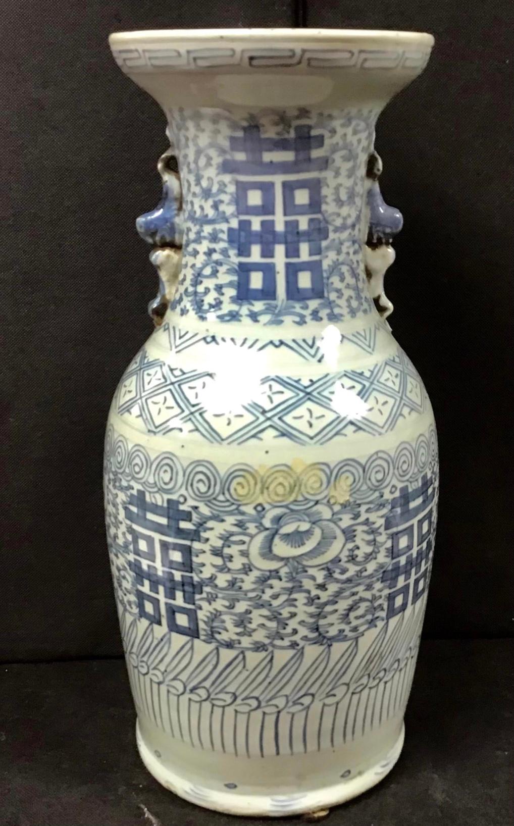 This blue-and-white porcelain vase stands tall with broad shoulders that taper to a splayed base. Bordered by a simple meander at the neck, the jar is decorated with a dense pattern of orchid blossoms and trailing vines. On each side of the jar, the