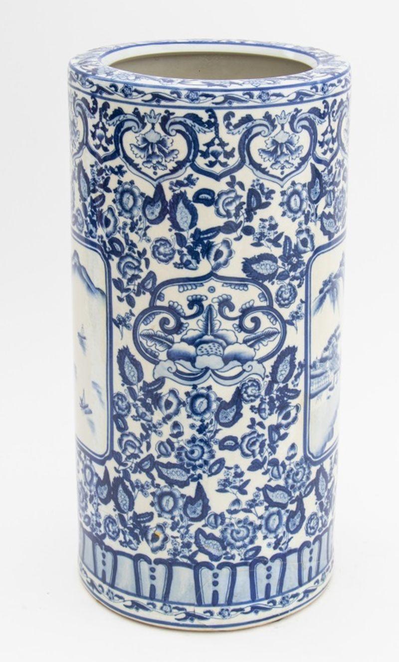 Porte-parapluies cylindrique en porcelaine chinoise bleue et blanche, avec des vignettes peintes de paysages entourées de motifs floraux, marque à six caractères sur le dessous. 18,5