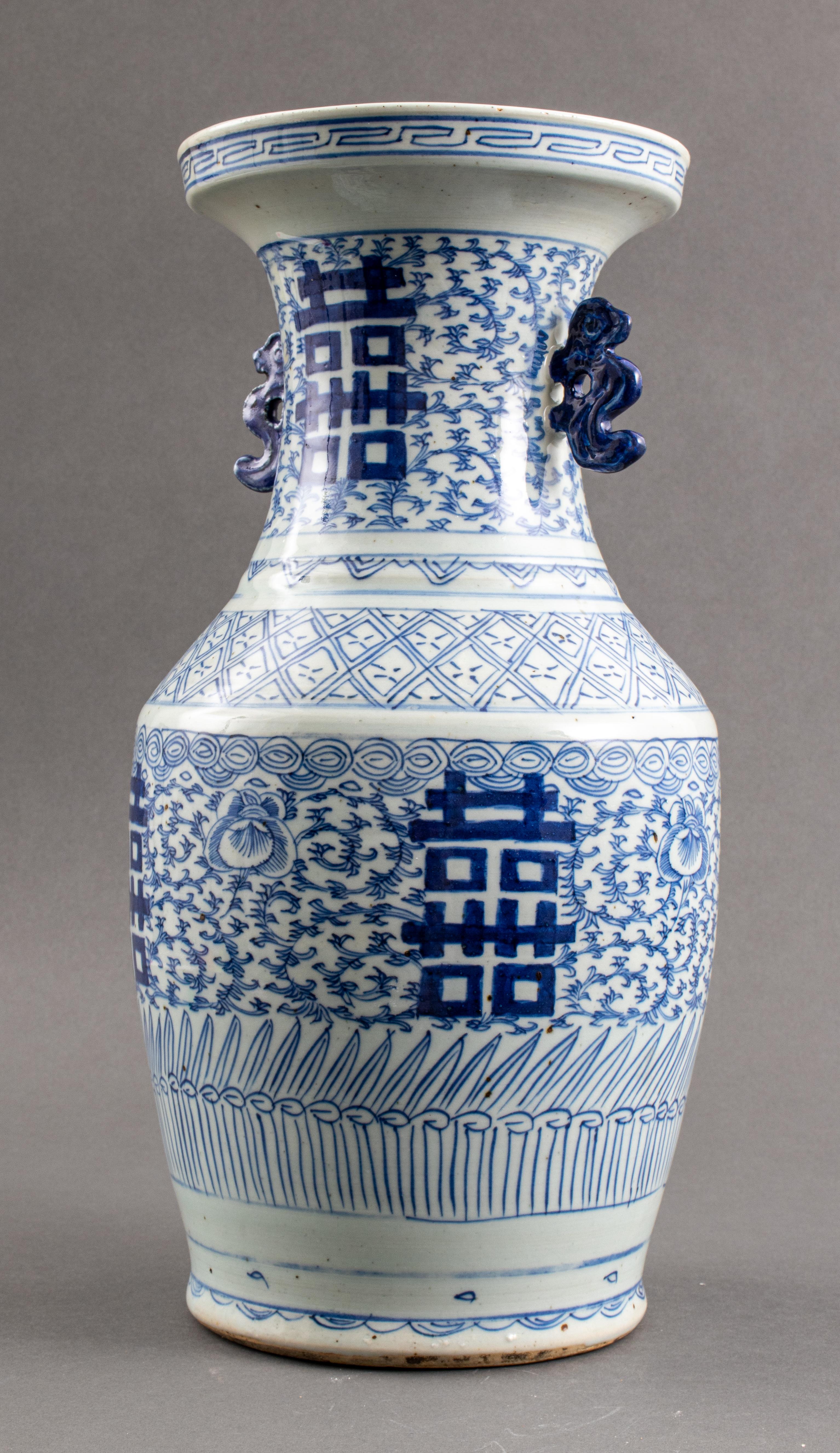 Chinesische Vase aus blauem und weißem Porzellan, handbemalt mit doppelten Glückssymbolen auf blattförmigem Grund, mit zwei figuralen Tierhenkeln, ungemarkt. 
Maße: 17,4