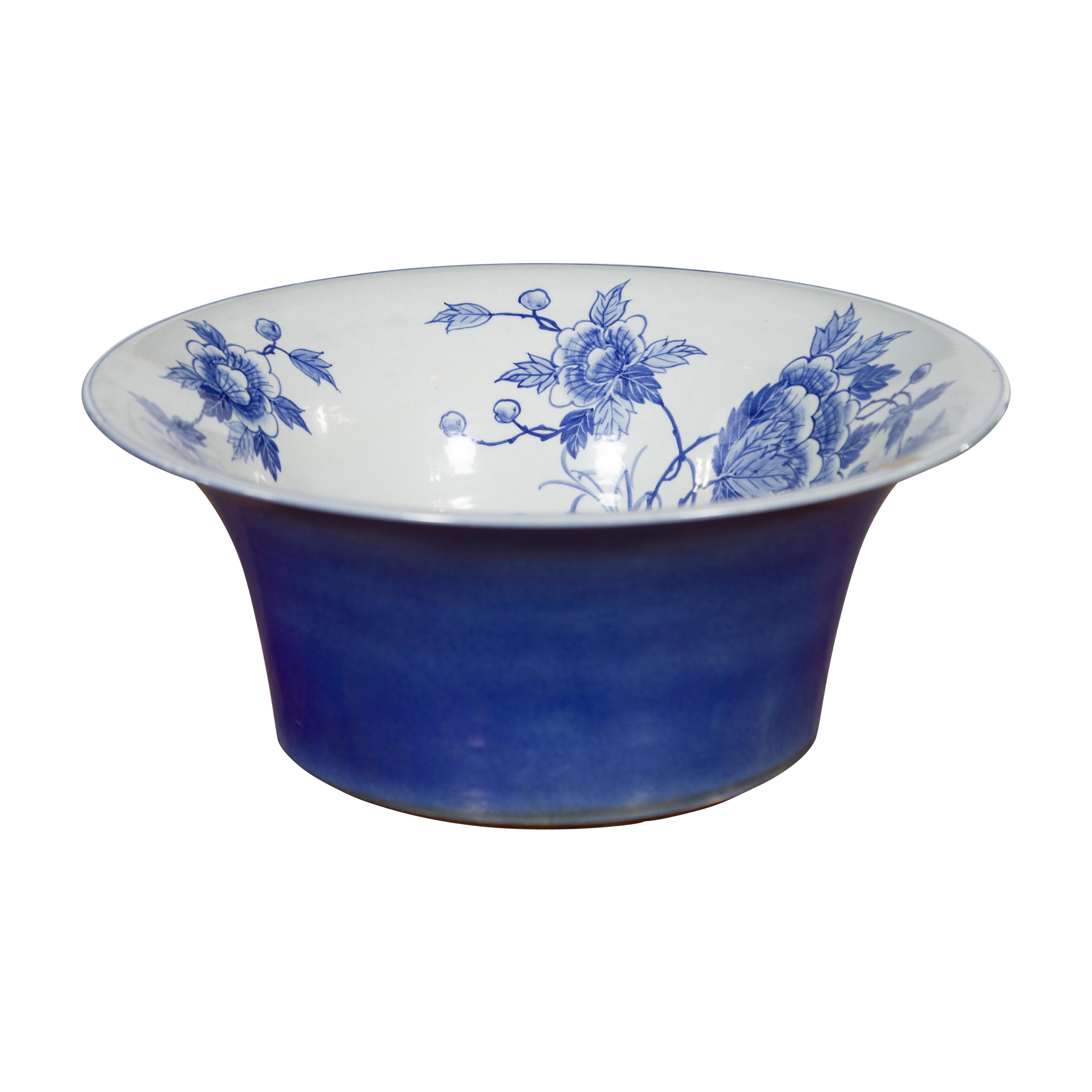 A Chinese porcelain wash basin from the 20th century, with hand-painted blue and white floral décor and cobalt blue flaring exterior. Created in China during the 20th century, this porcelain wash basin features a flaring silhouette adorned on the