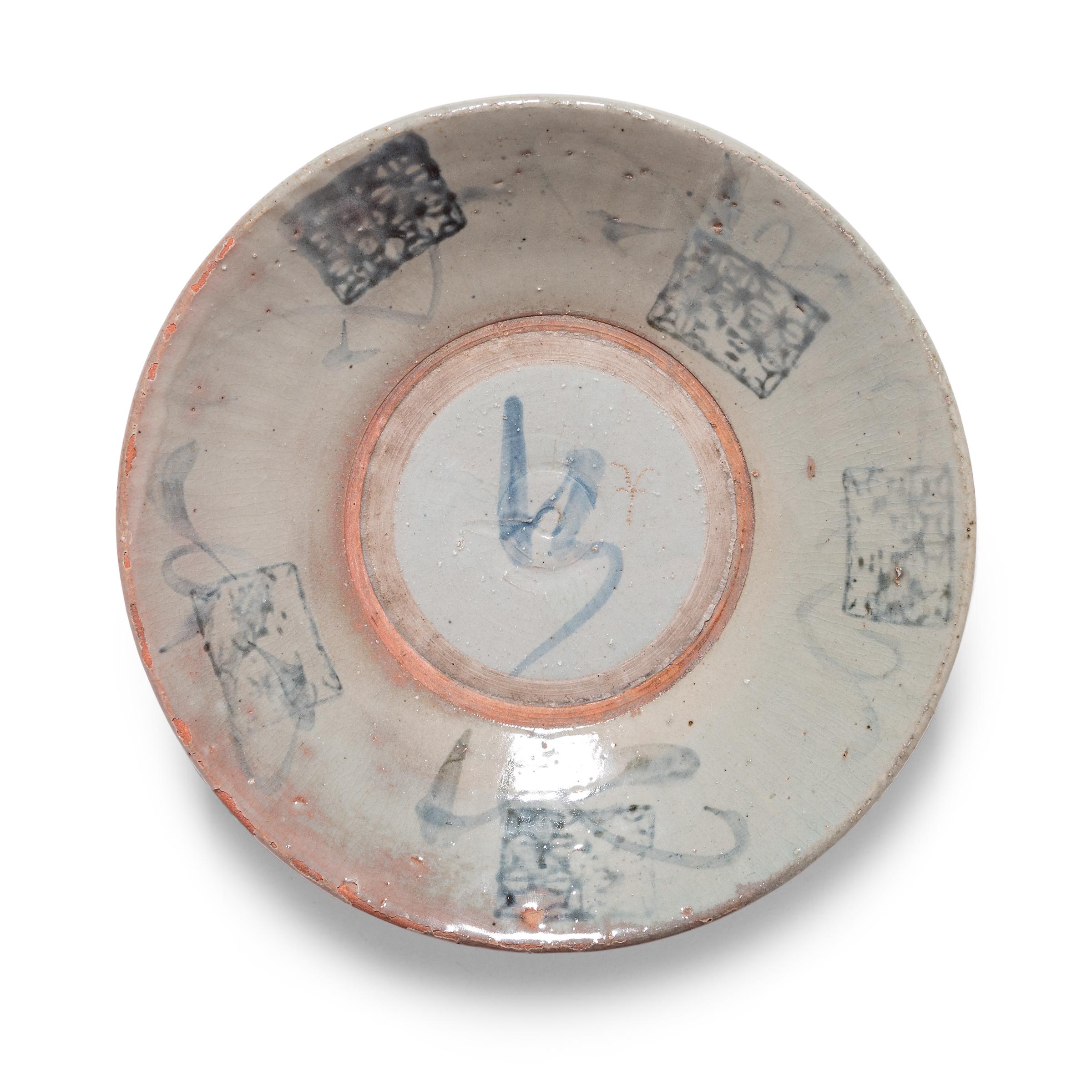 Calligraphic sweeps of blue bring this early 20th century footed plate to life, adorning the crazed blue-grey glaze that cloaks its terracotta form. Atop the freeform brushwork is a lattice-like pattern of coin motifs, likely applied with a stamp.