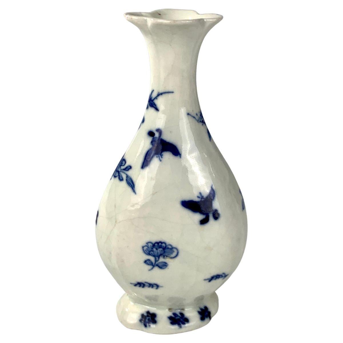 This delicate Chinese blue and white bud vase was made in the early 18th century.
Hand-painted in shades of cobalt blue, it shows peonies emanating from rockwork.
The vase has an elegant, slender form that rises to a flared lotus form rim. It is