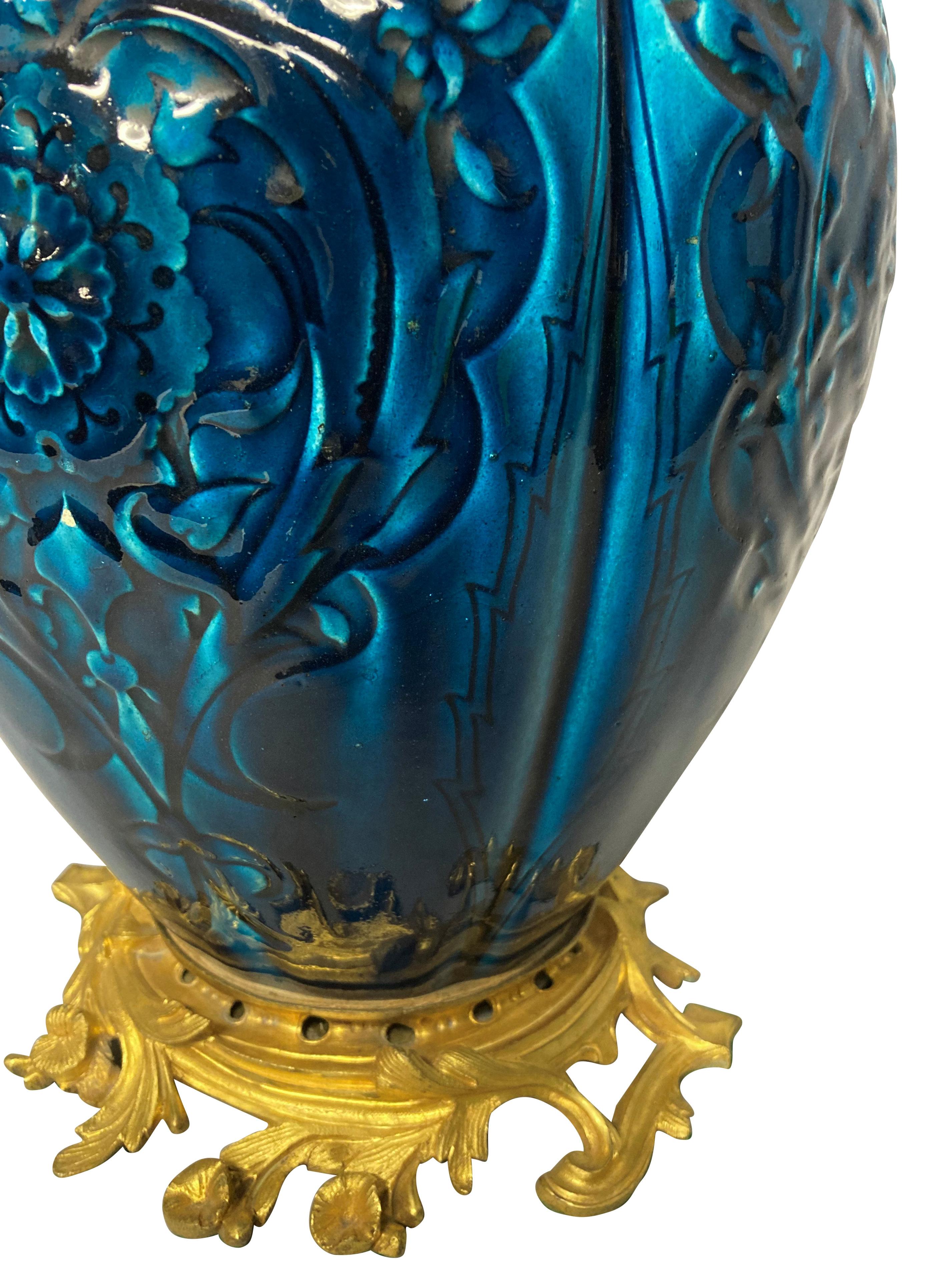 A Chinese blue glazed ceramic porcelain vase with floral decoration, mounted on an a finely cast gilt bronze stand, with gilt bronze and brass fittings.