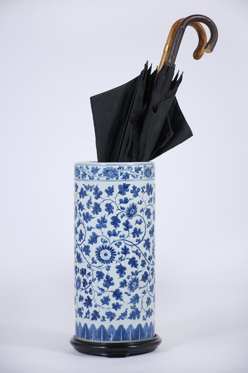An extraordinary Chinese umbrella stand crafted out of porcelain in great condition. This vase features remarkable hand-painted flowers and leaves details design, resting on a carved wood base with an ebonized finish. This eye-catching umbrella