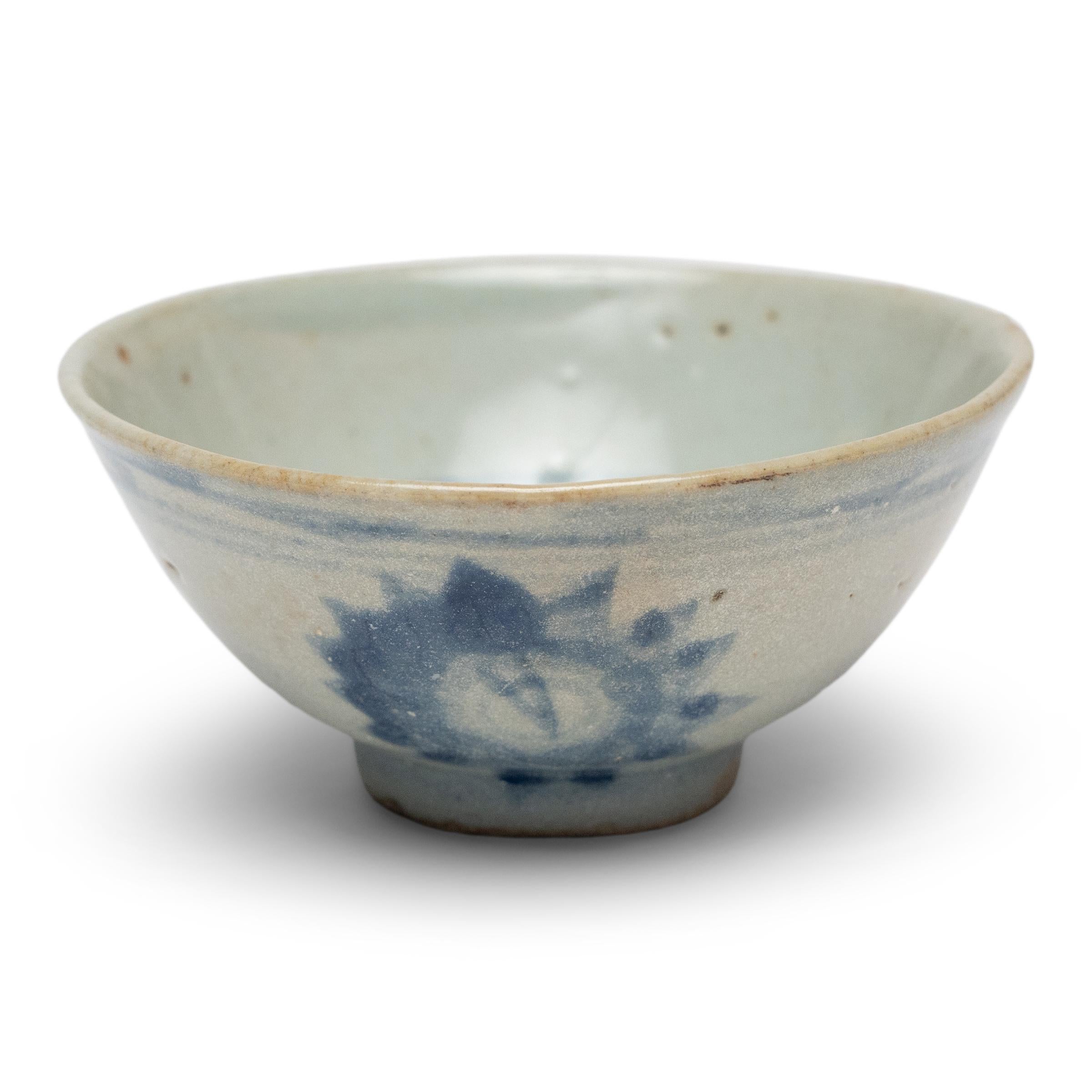 An everyday example of Chinese blue-and-white ceramics, this petite cup from the late Qing dynasty is appreciated for its delicate simplicity and charming imperfections. Used for drinking tea or rice wine, the small cup has a tea-bowl silhouette,