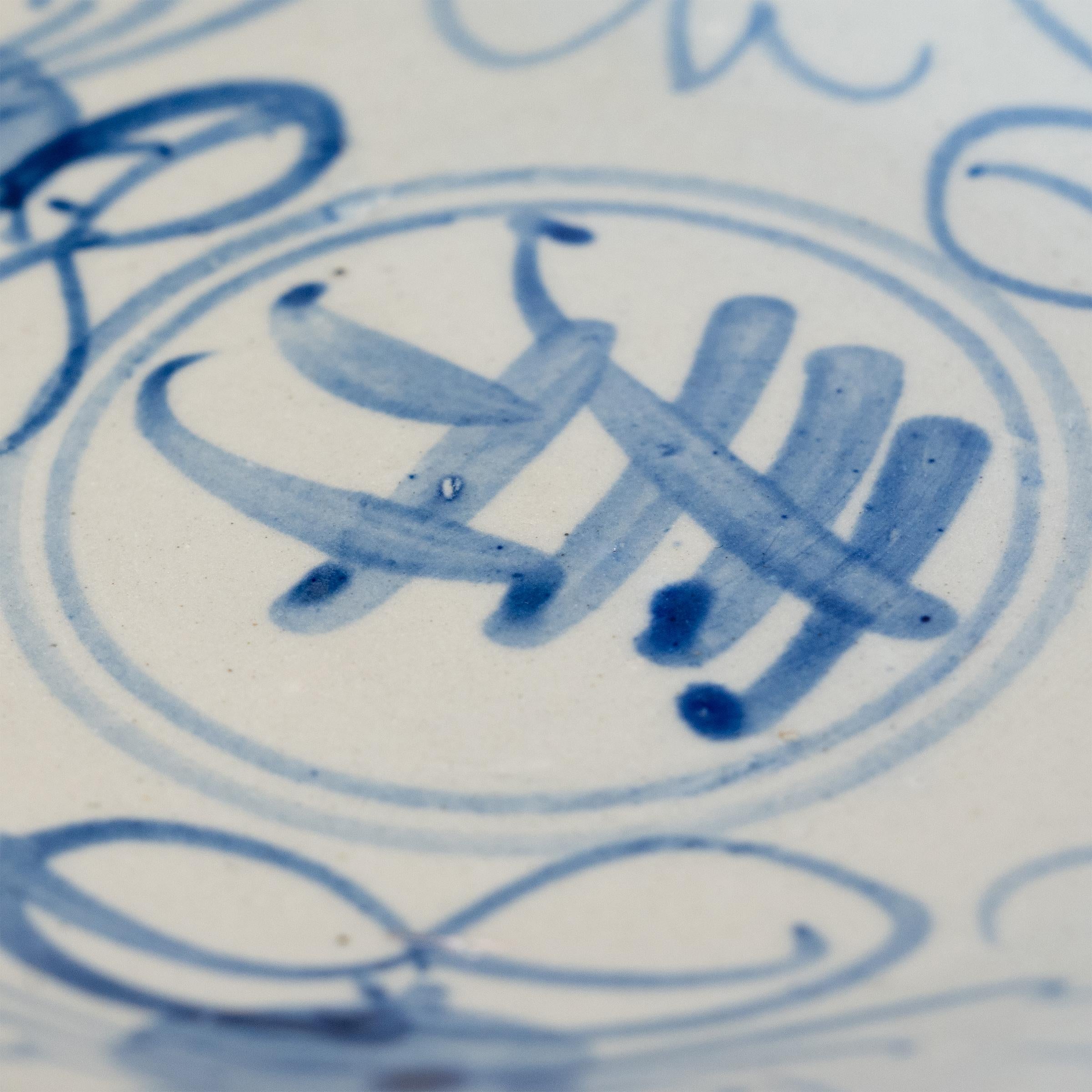 An everyday example of Chinese blue-and-white porcelain, this vintage porcelain plate charms with expressive cobalt-blue decoration, loosely brushed against a blue-grey field. The plate is decorated with a large Shou character at the center, a