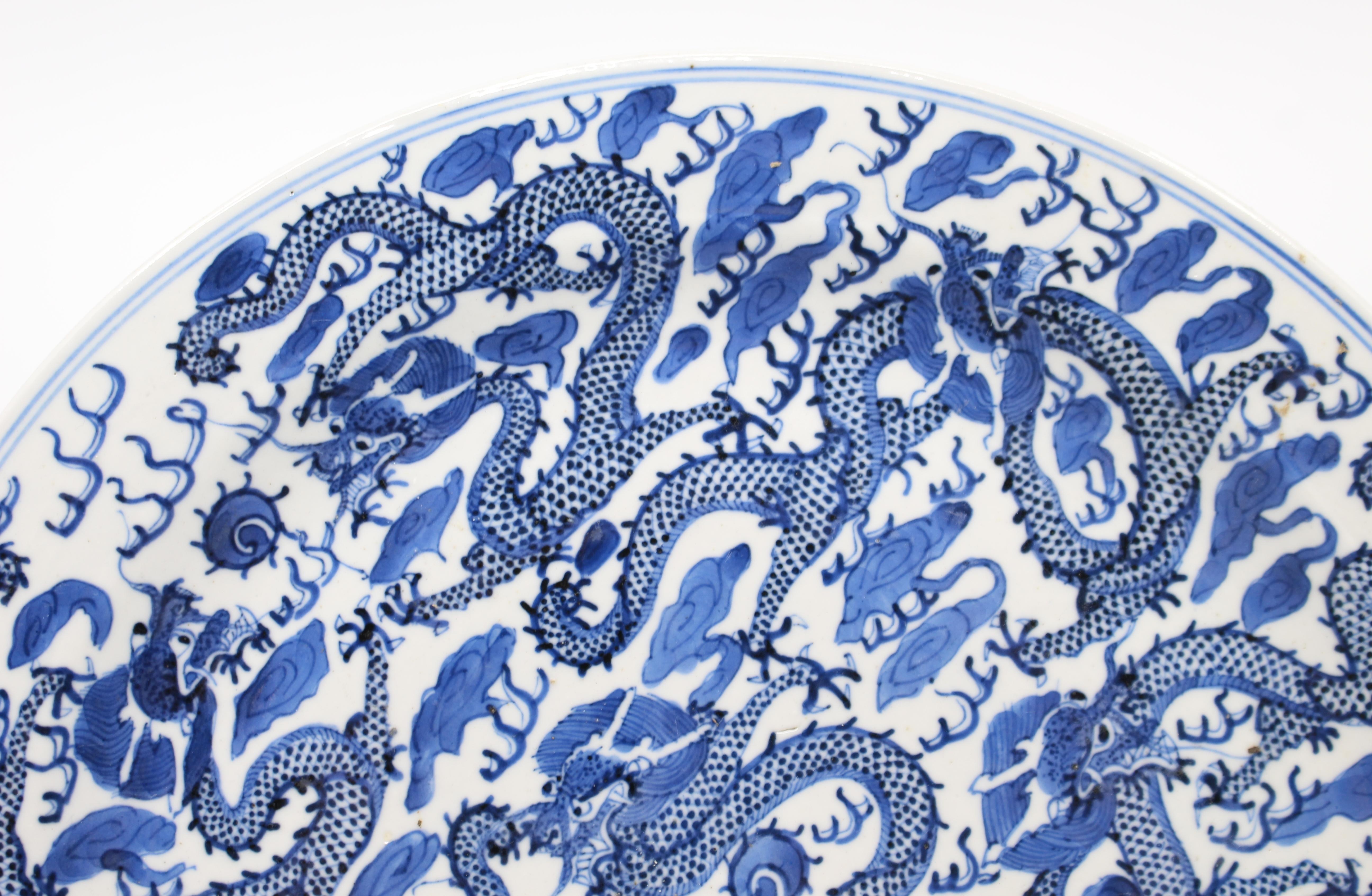 Period 
Kangxi (1662-1722)

Origin 
Chinese

Decoration
Blue and white, dragons

Measures: Diameter 
29 cm / 11 1/2 in

Condition 
Good condition. Slight old small nick to border. A few marks underglaze commensurate with period

