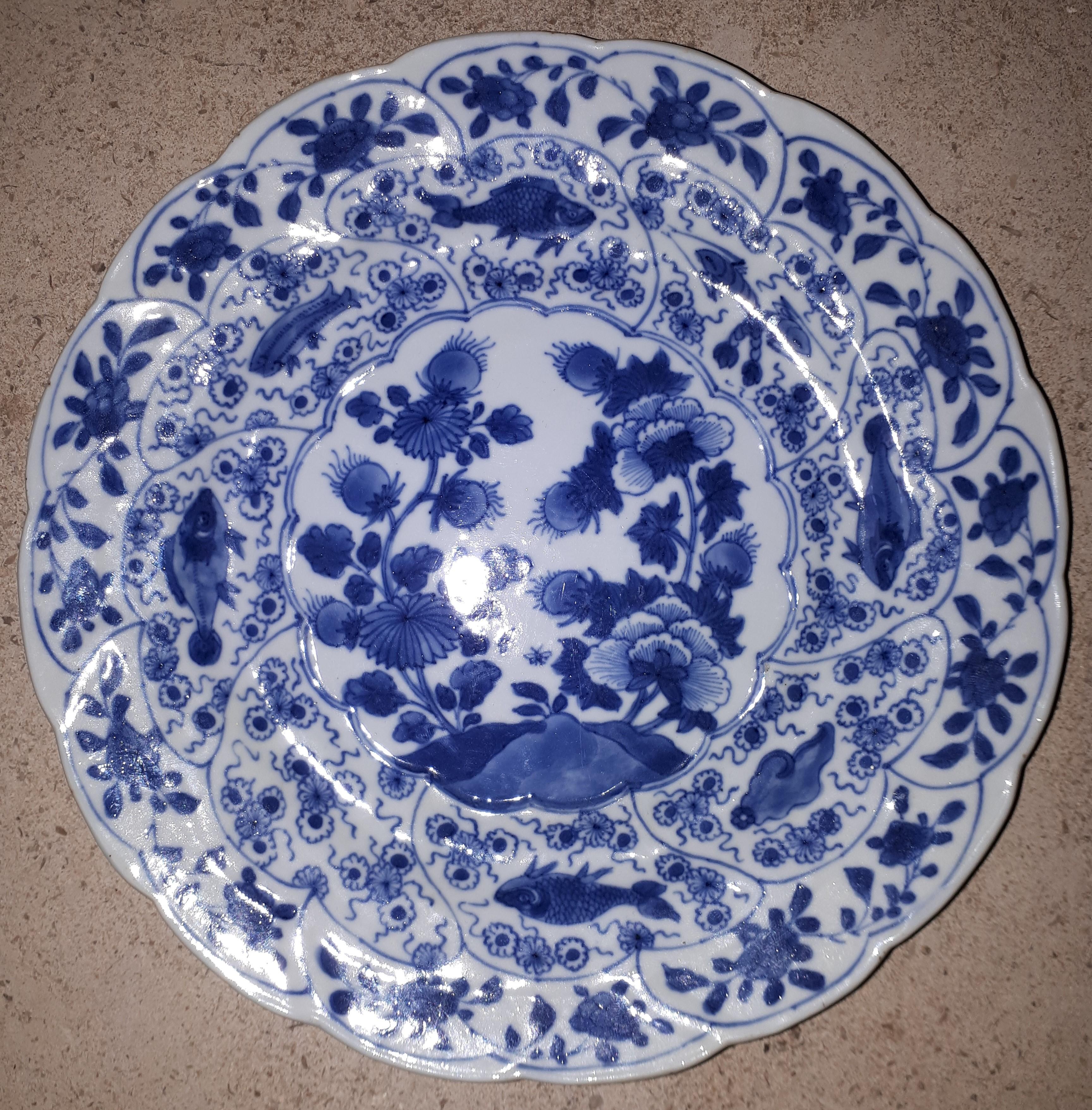 Rare porcelain plate with underglaze blue decoration of peonies, the wing decorated with crustaceans, fish and flowers in reserves.
China, late 17th century.