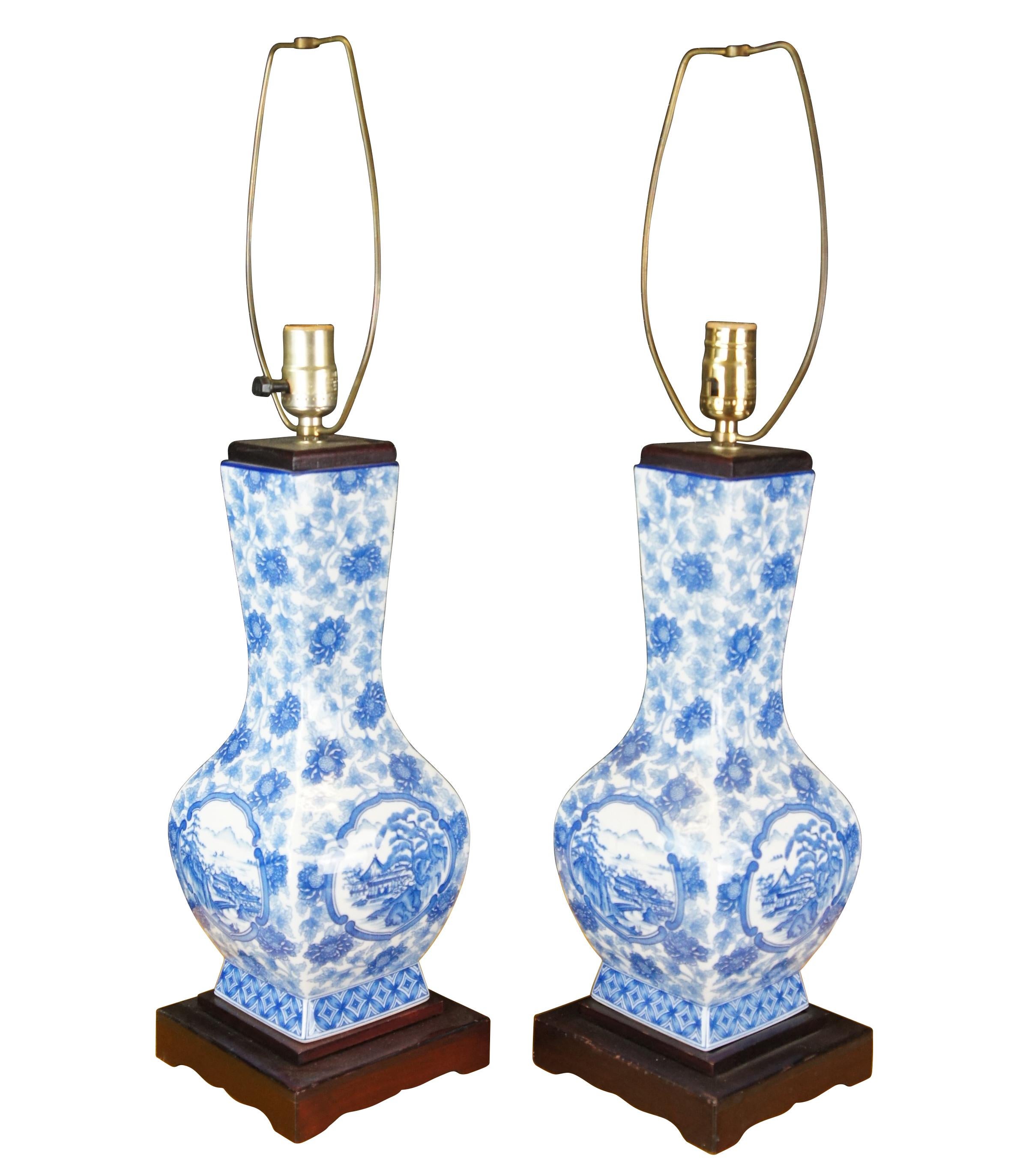 An elegant pair of Chinese table lamps in the form of a vase or urn. The blue and white porcelain vases features a field of Chrysanthemums with a pagoda landscape scene. Each lamp is on a wooden base.